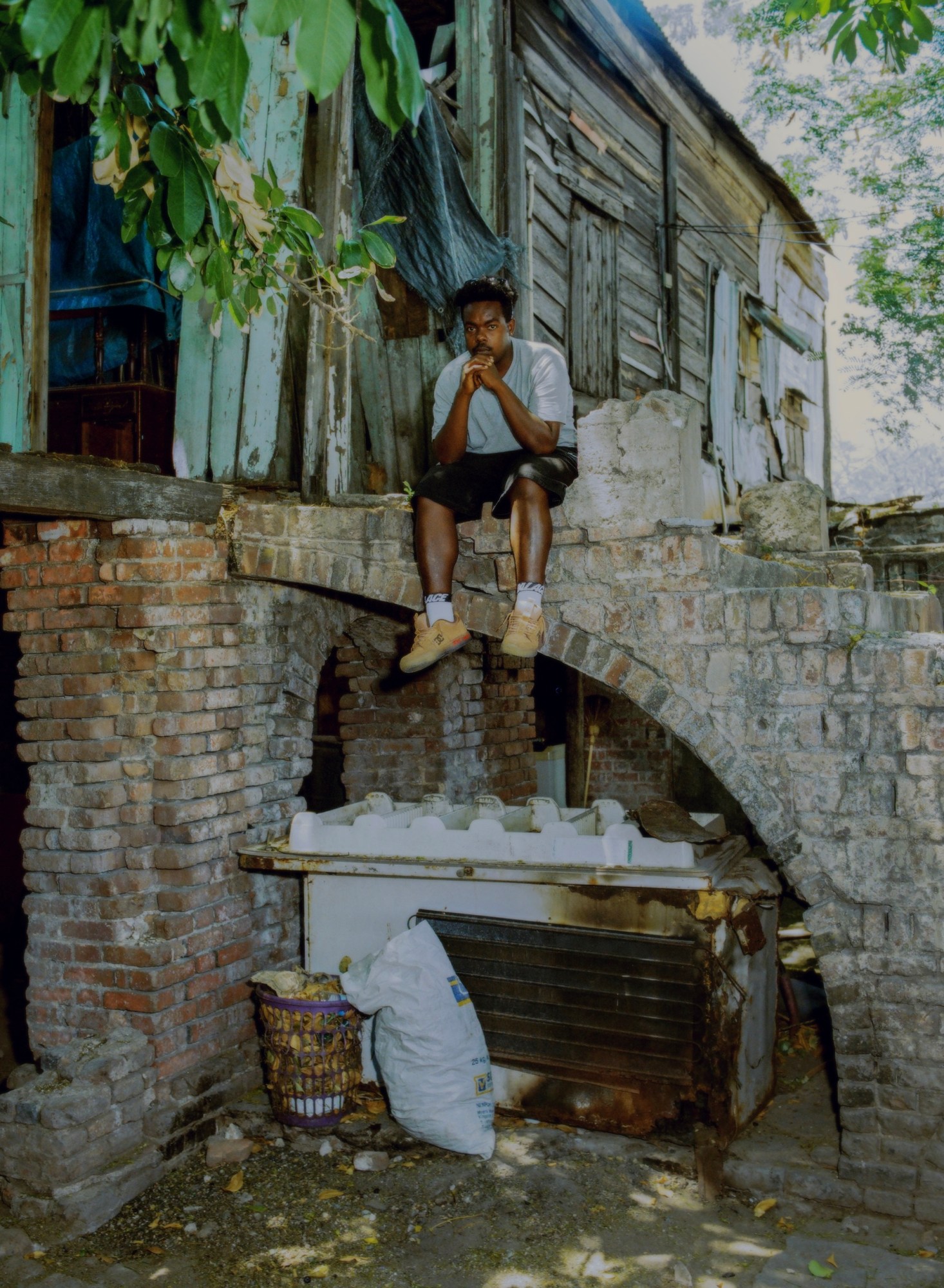 Photograph by Julian Klincewicz of a man sitting on an old, crumbling stair case in an old house wearing DCV'87