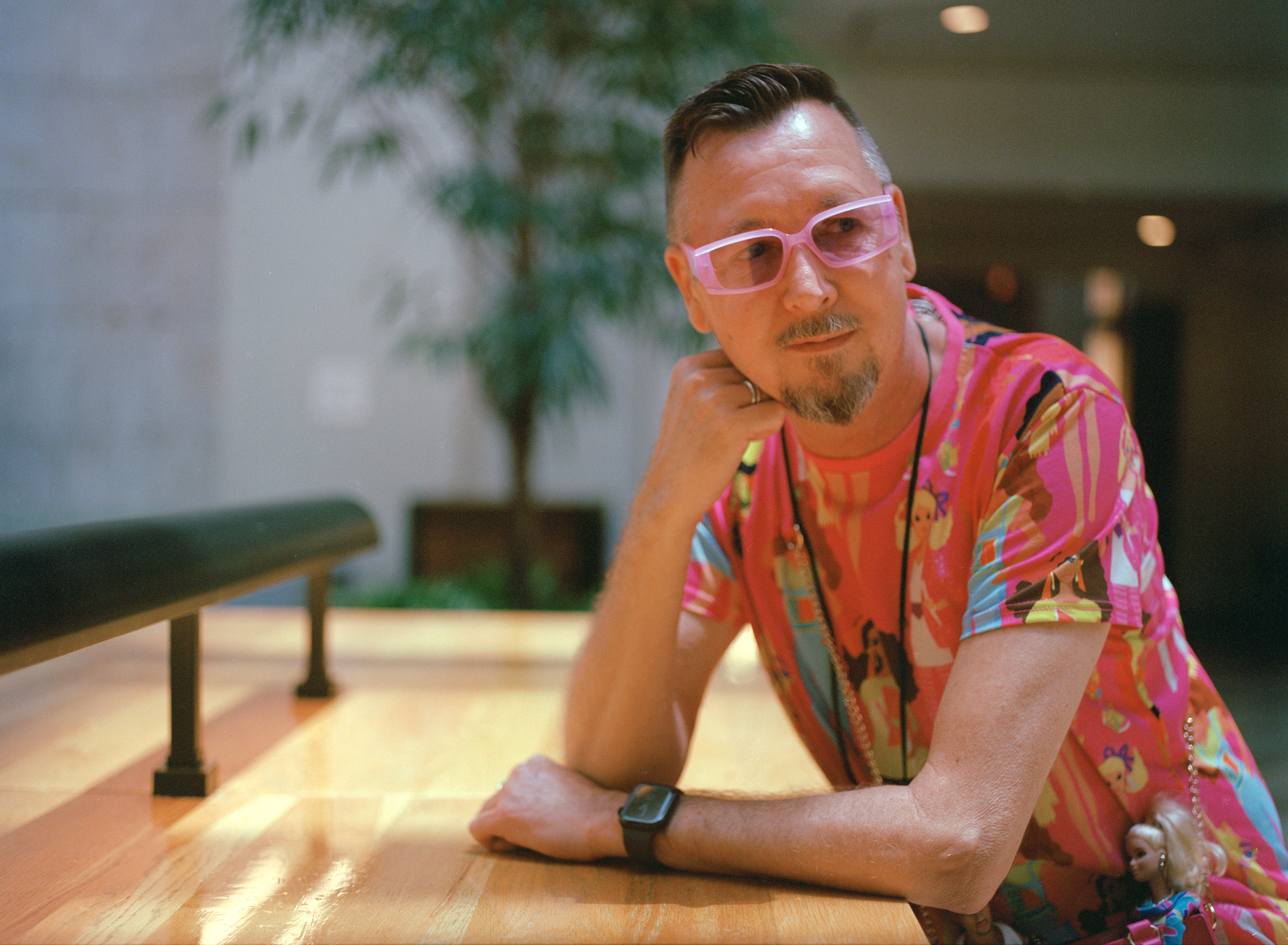 a man in pink glasses and a pink shirt covered in images of barbie