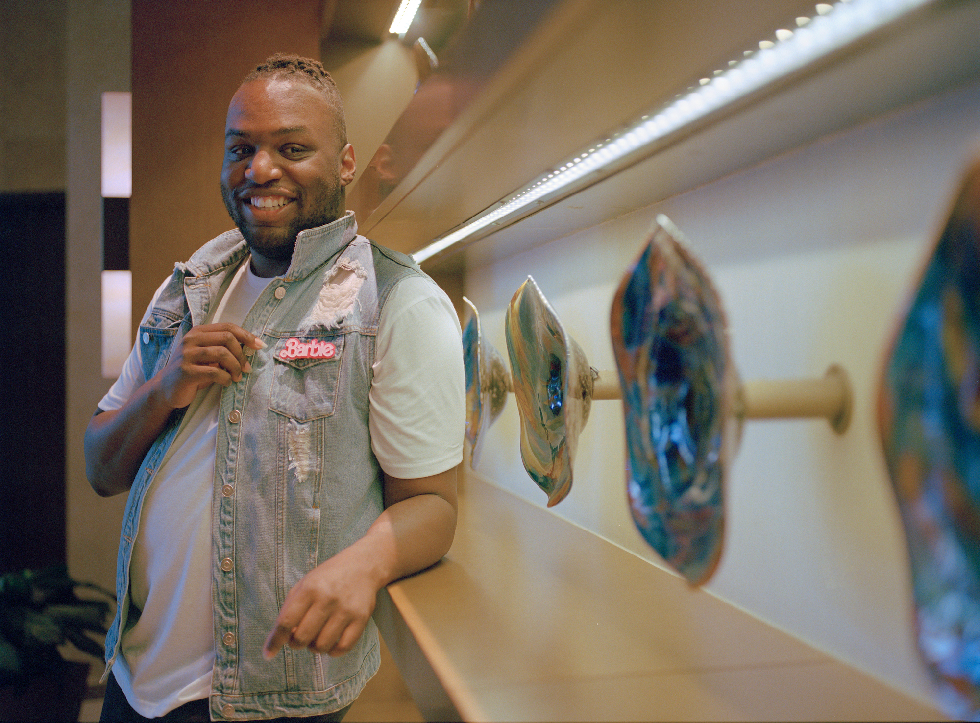 a man in a denim vest with a pink barbie pin