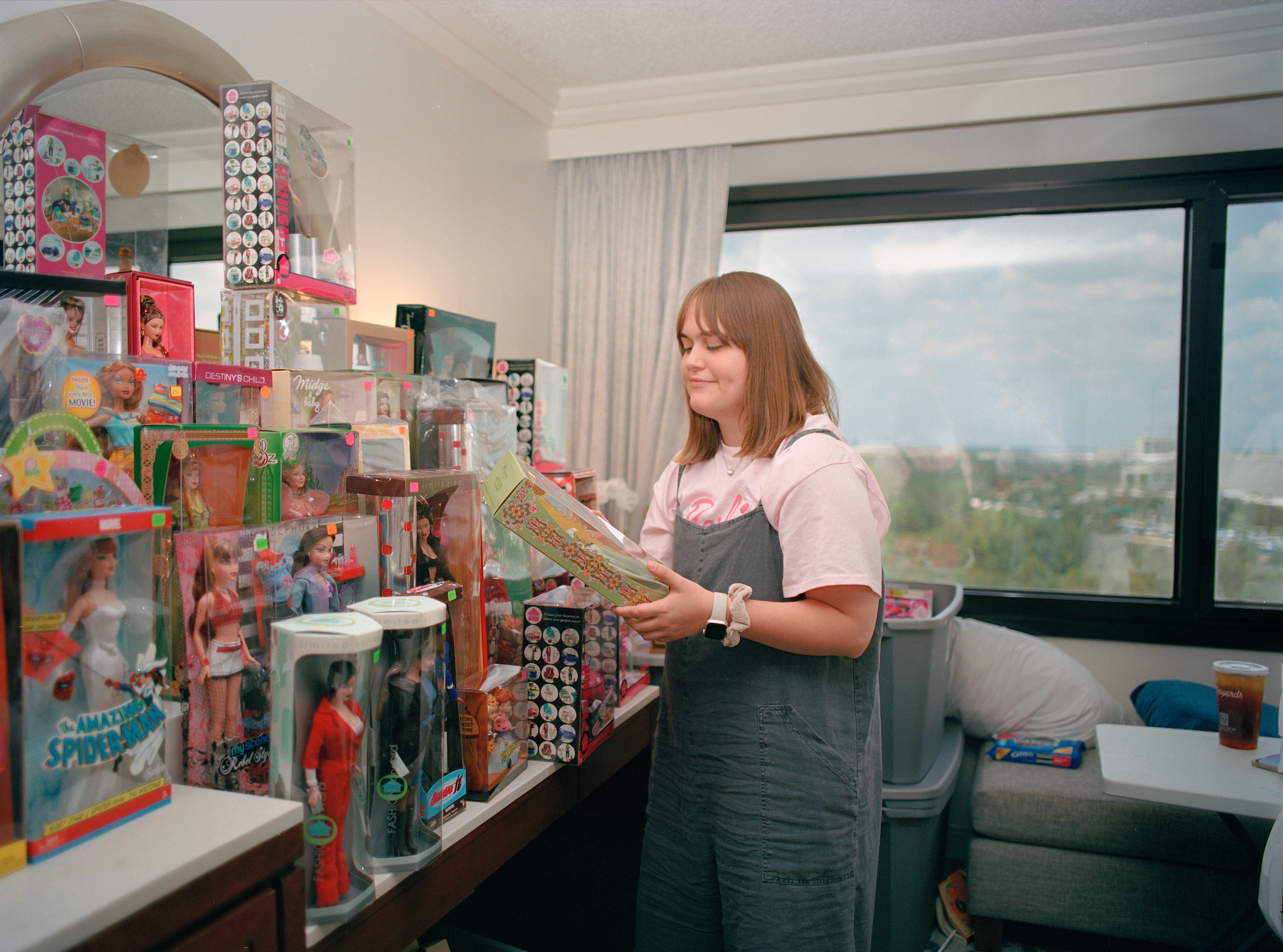 a young woman standing next to a tower of vintage barbies