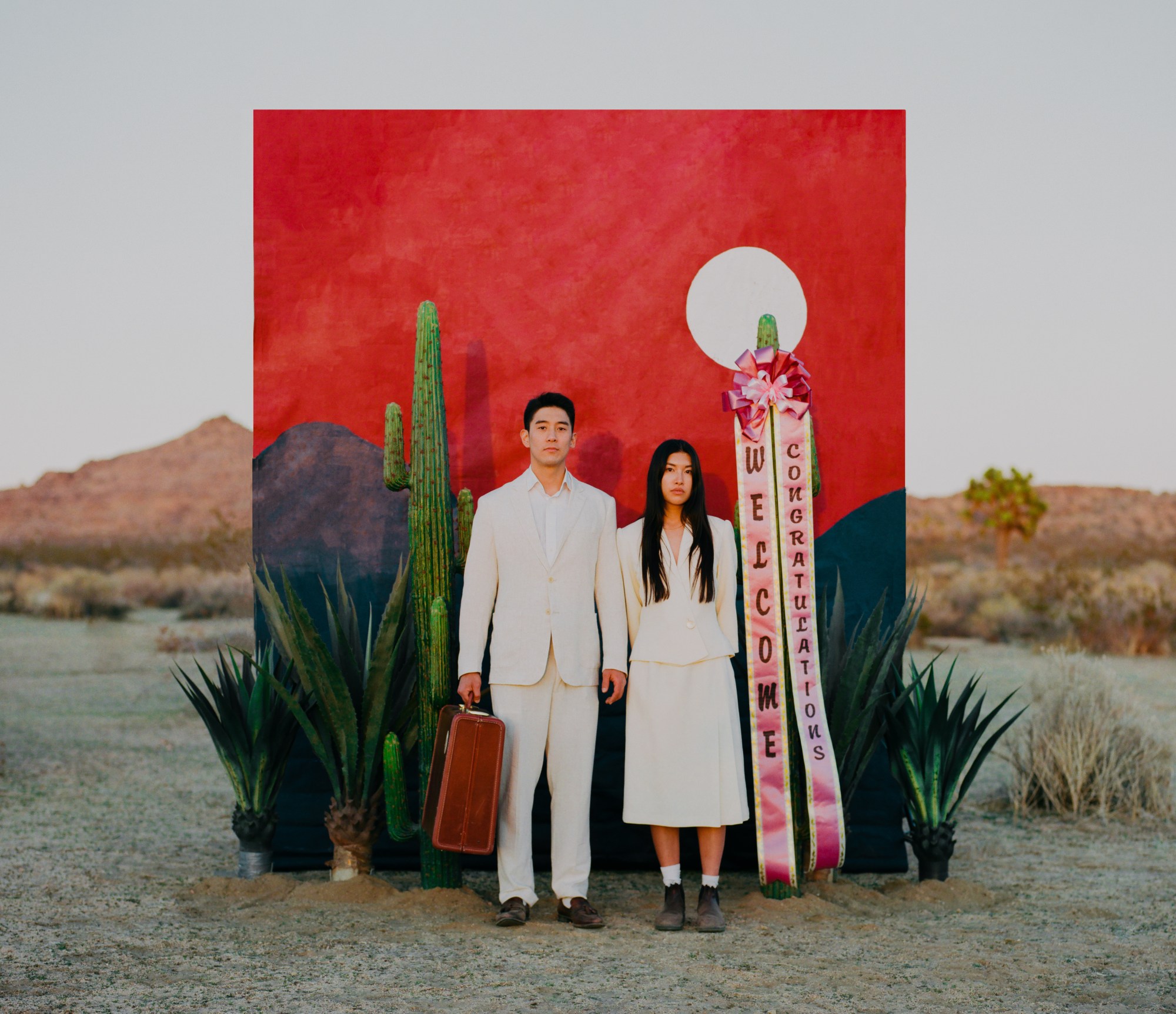 a couple dressed in white clothes standing side by side in the desert