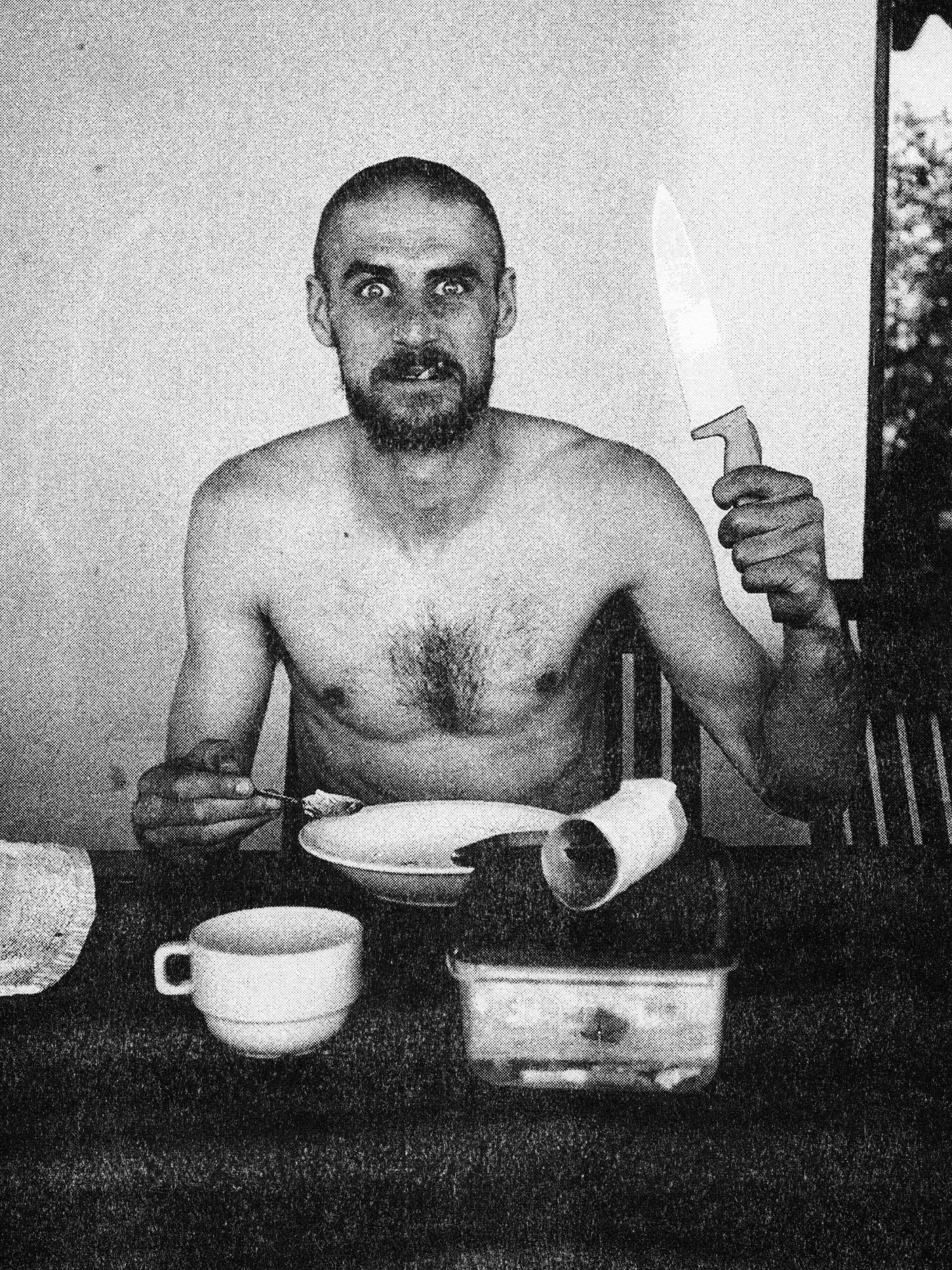 a man at a table eating food with a large knife