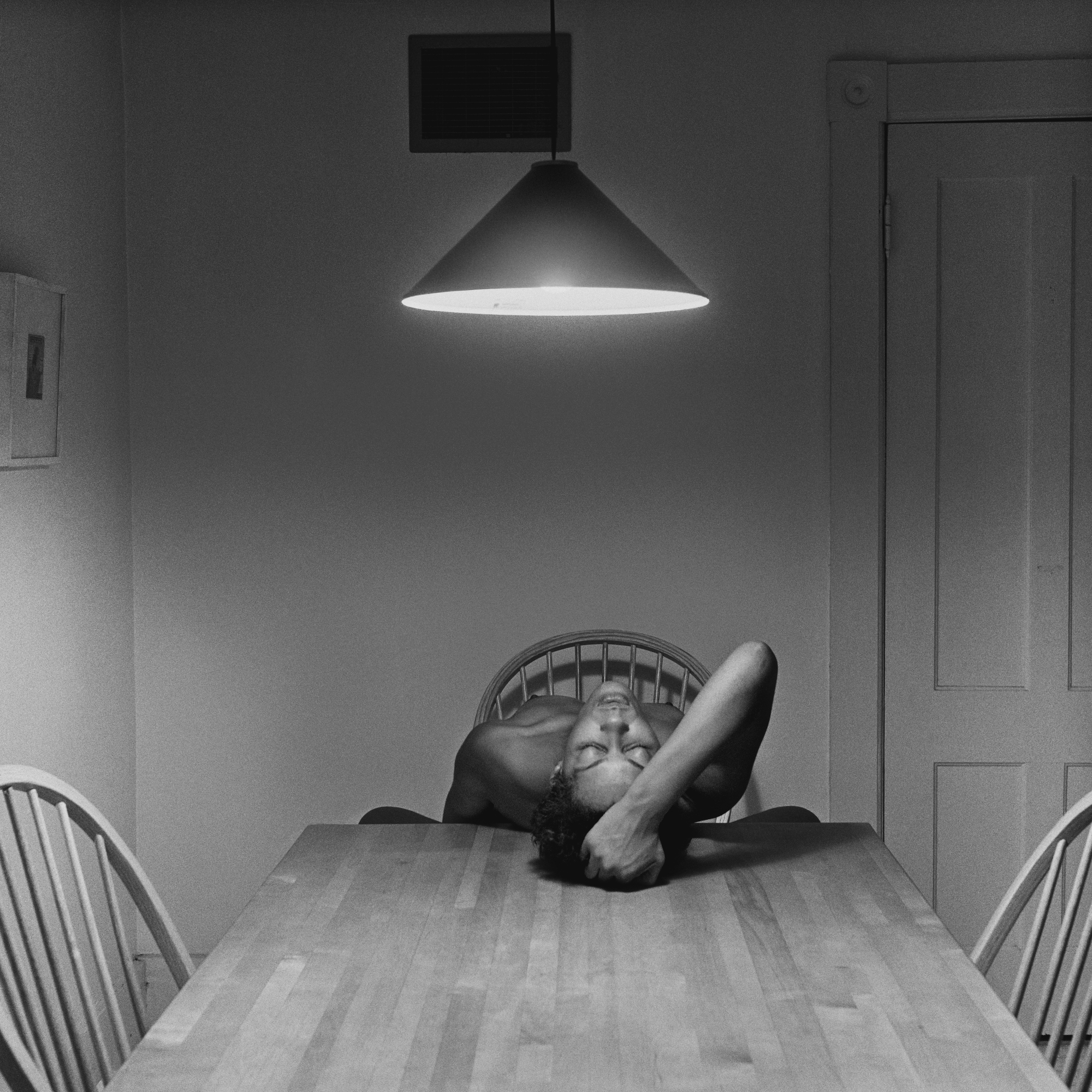 Carrie Mae Weems posing nude for a self portrait at a kitchen table