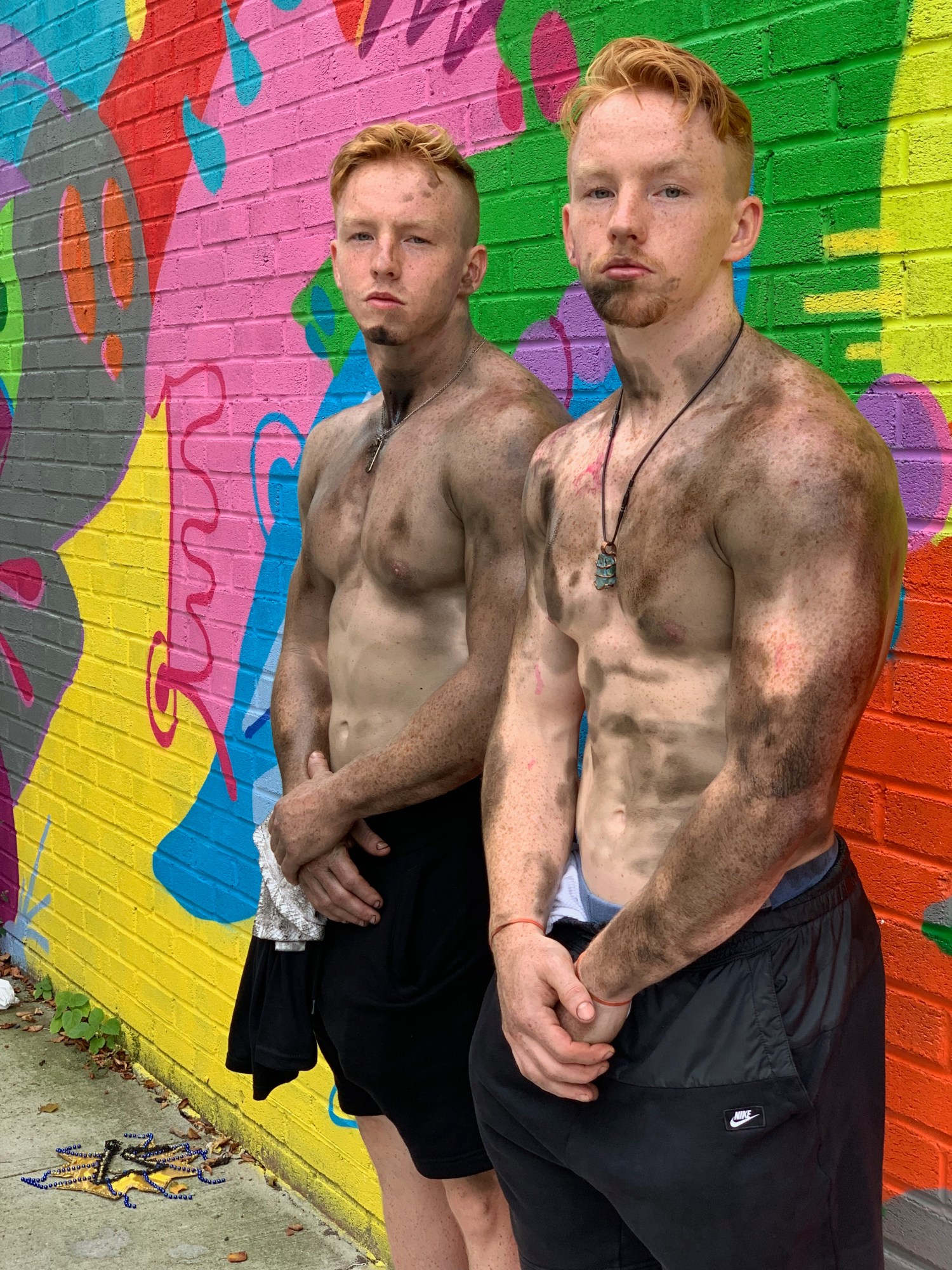 Photograph from End of the Line by Taylor Chapman of two blonde boys shirtless covered in mud and standing by a painted wall