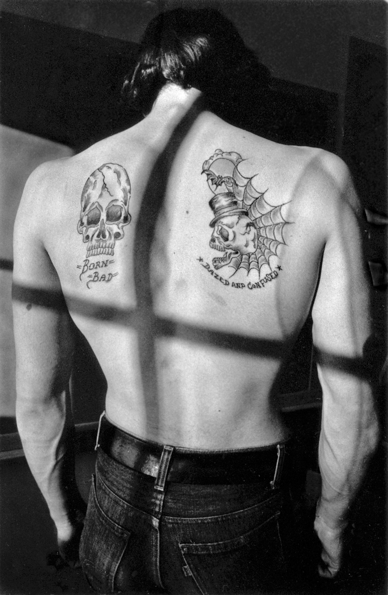 a back with tattoos that say dazed and confused and born bad in black and white