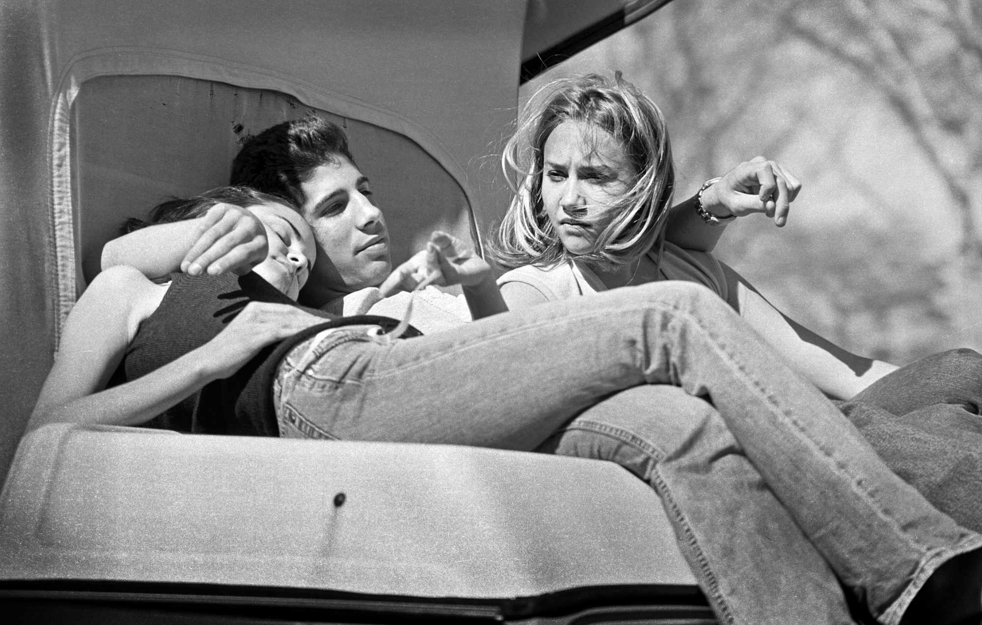 three people sitting on a bench in jeans outside in the 90s