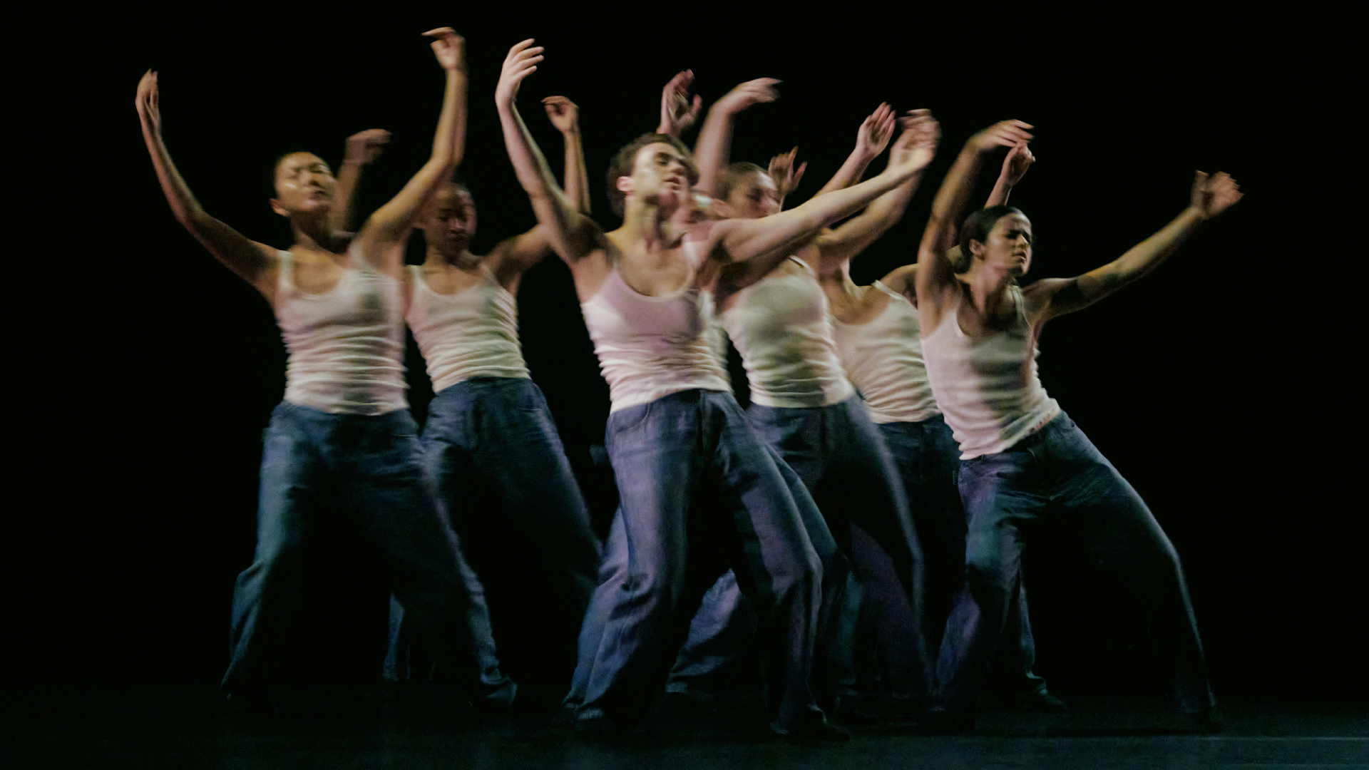 a group of dancers in bottega veneta white tank tops and blue denim with their arms raised