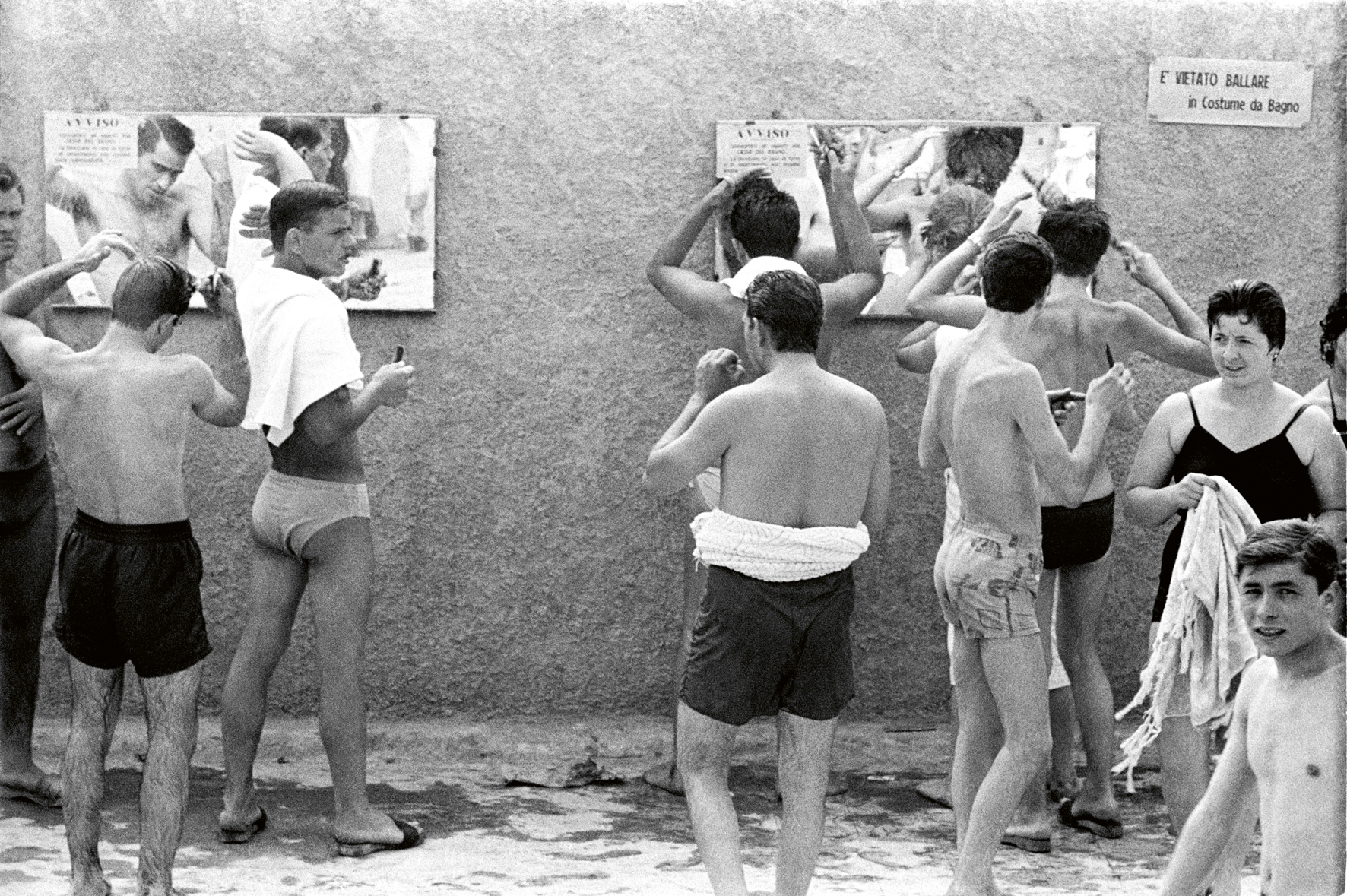 a black and white photograph by paolo di paolo of bathers at a lido looking in the mirror to fix their hair.