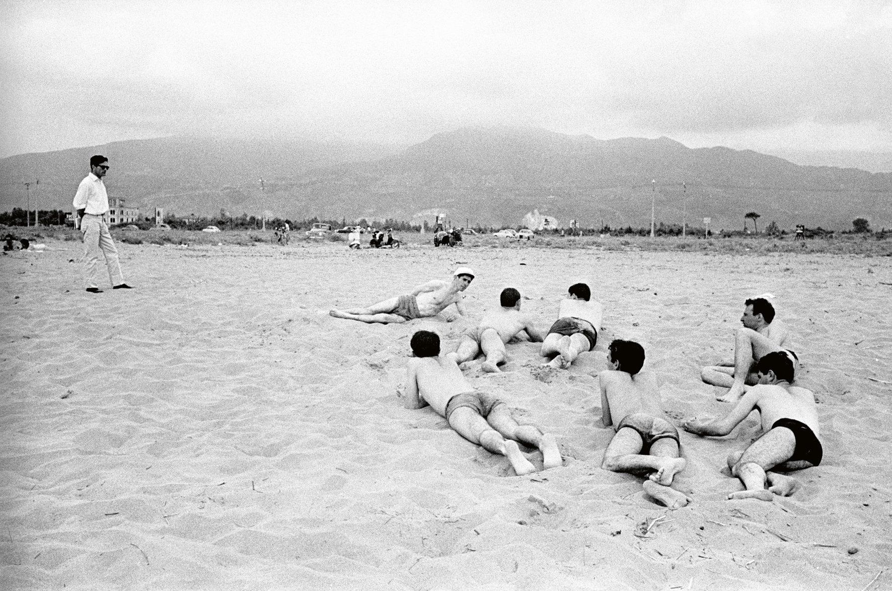 a black and white photograph by paolo di paolo of sunbathing men in swimshorts on the beach