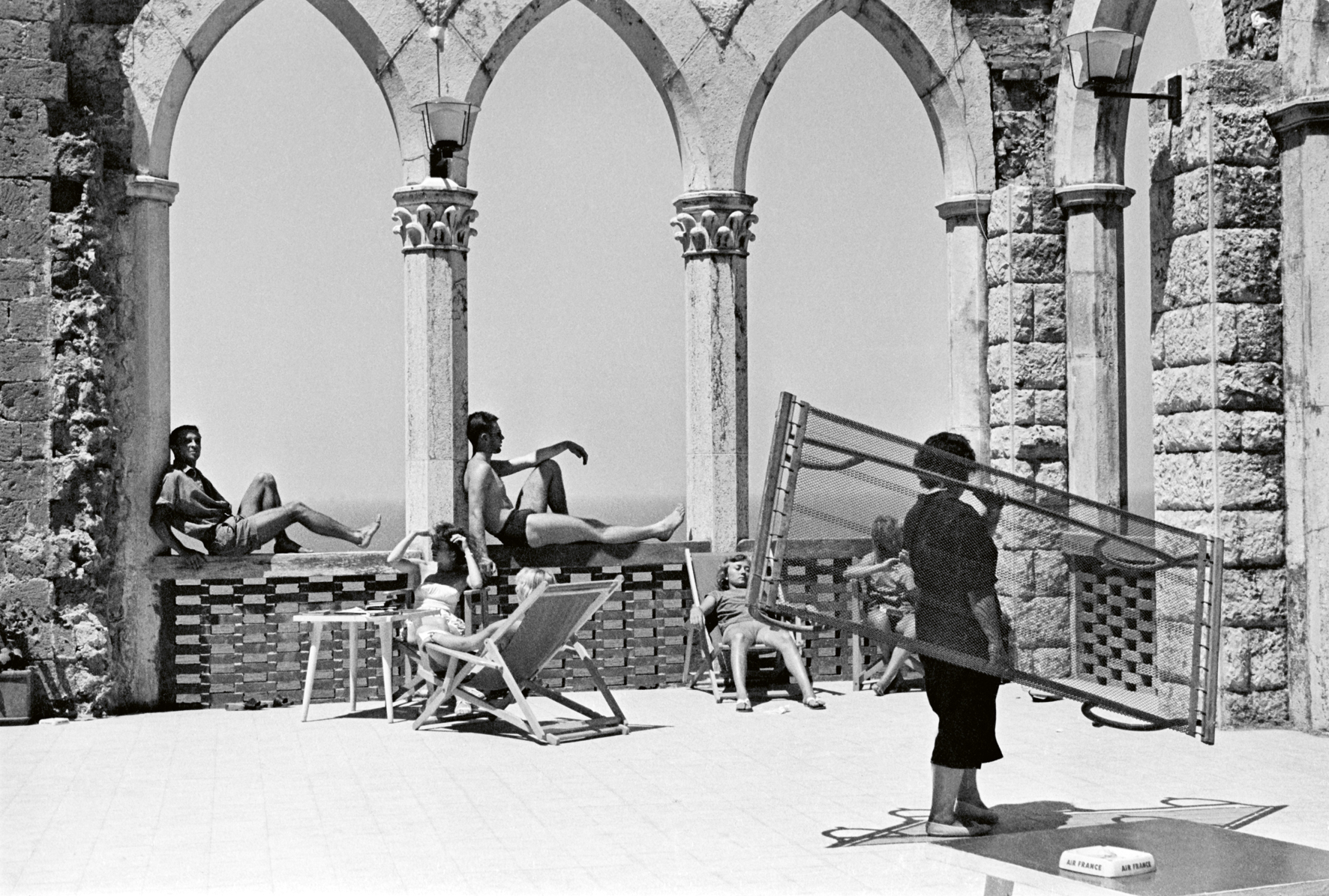 a black and white photograph by paolo di paolo of sunbathers in an old structure in sorrento.