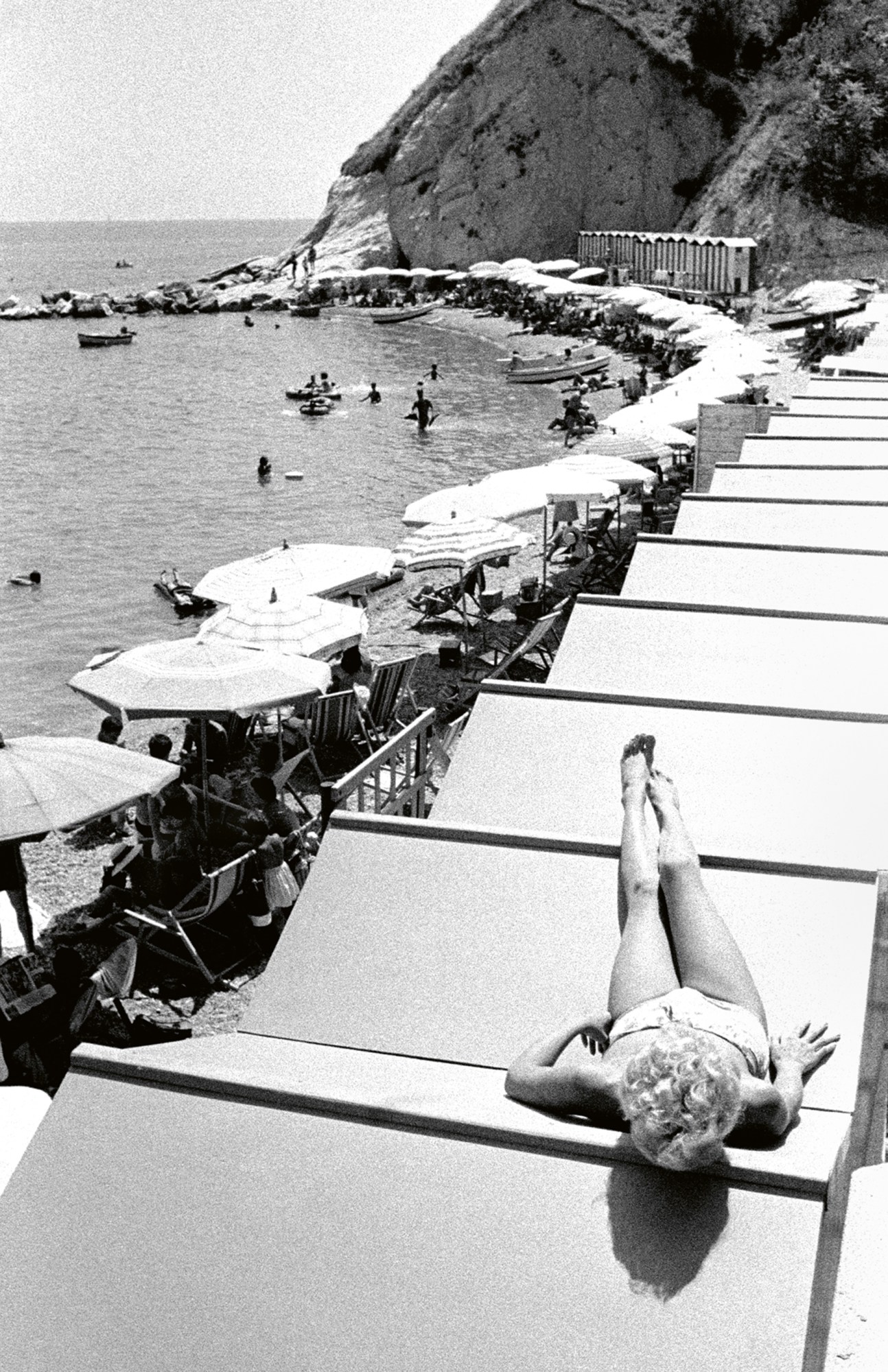 a black and white photograph by paolo di paolo of a woman sunbathing on the roof of sunhuts