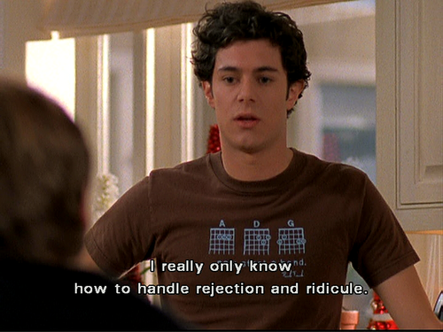 seth cohen in a still from the oc wearing a vintage tee with subtitles reading: I really only know how to handle rejection and ridicule.