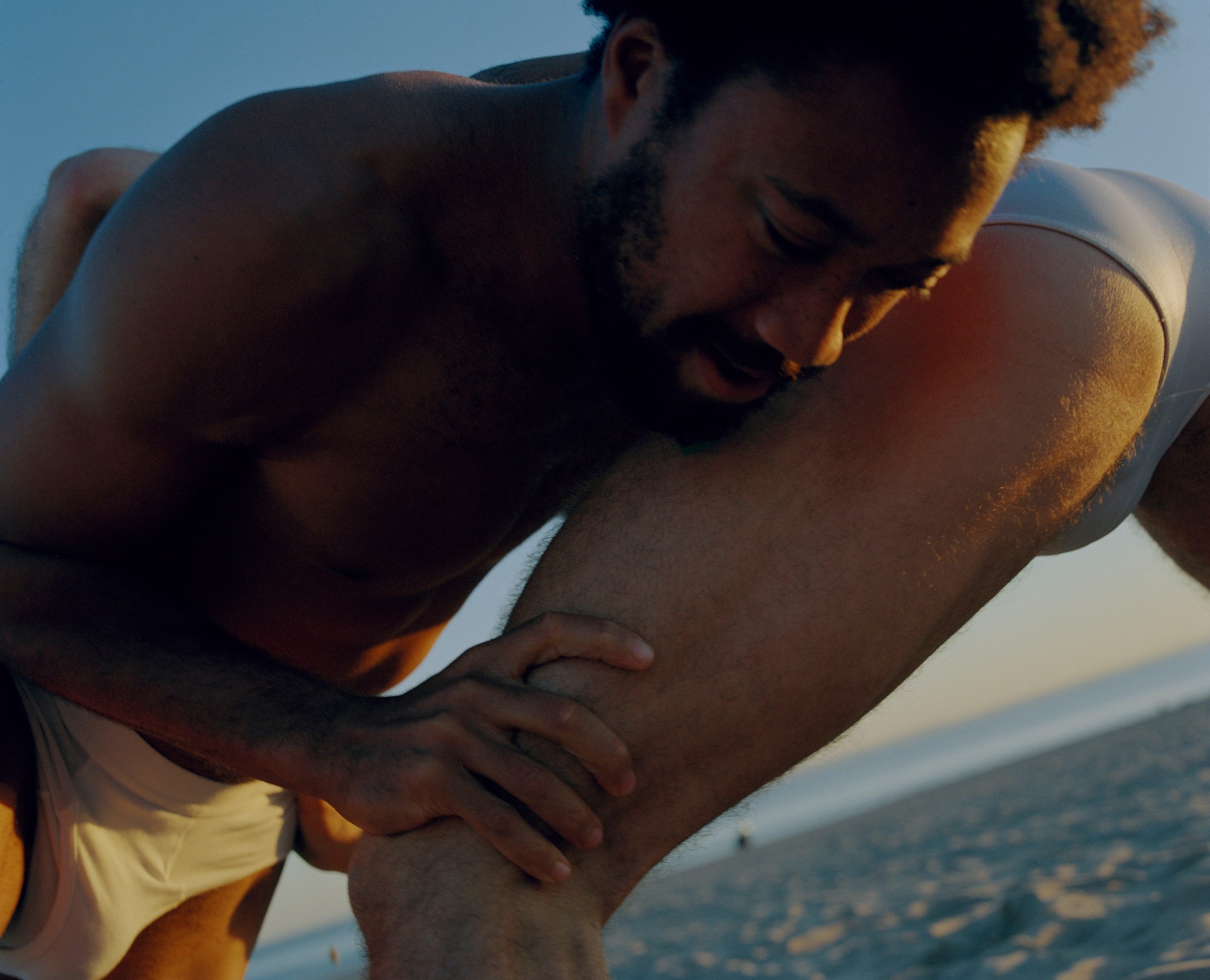 two men in underwear wrestling on a beach