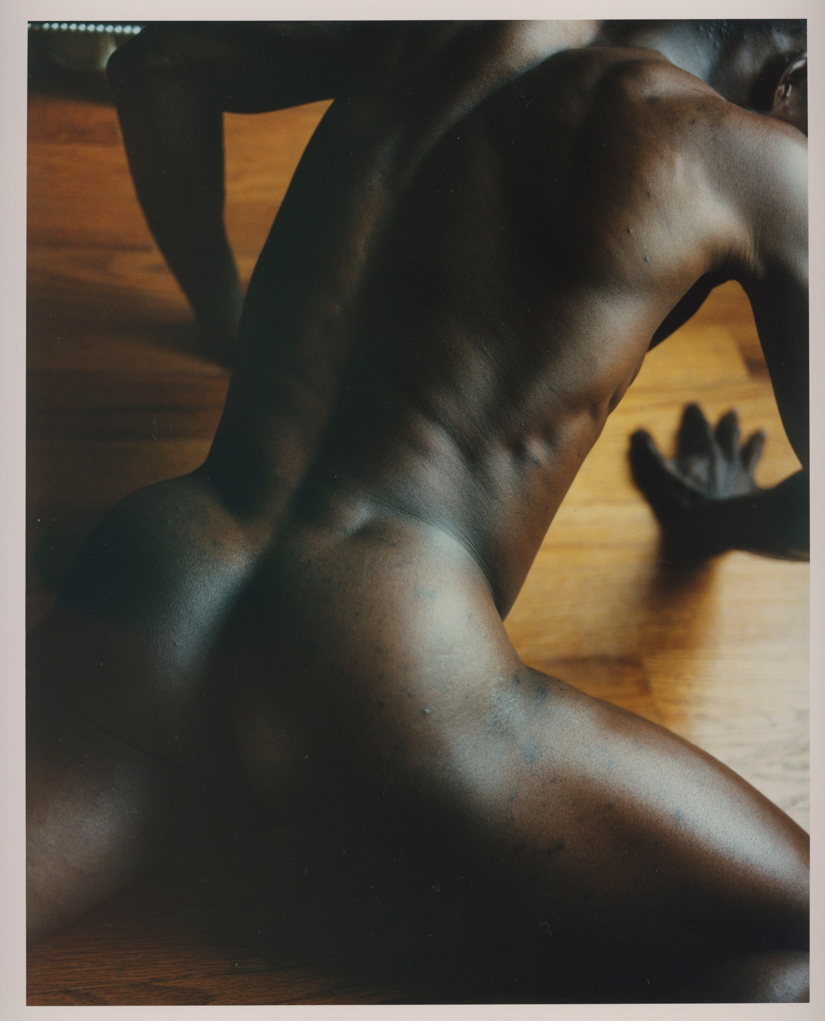 a naked man seen from above crawling on a wooden floor