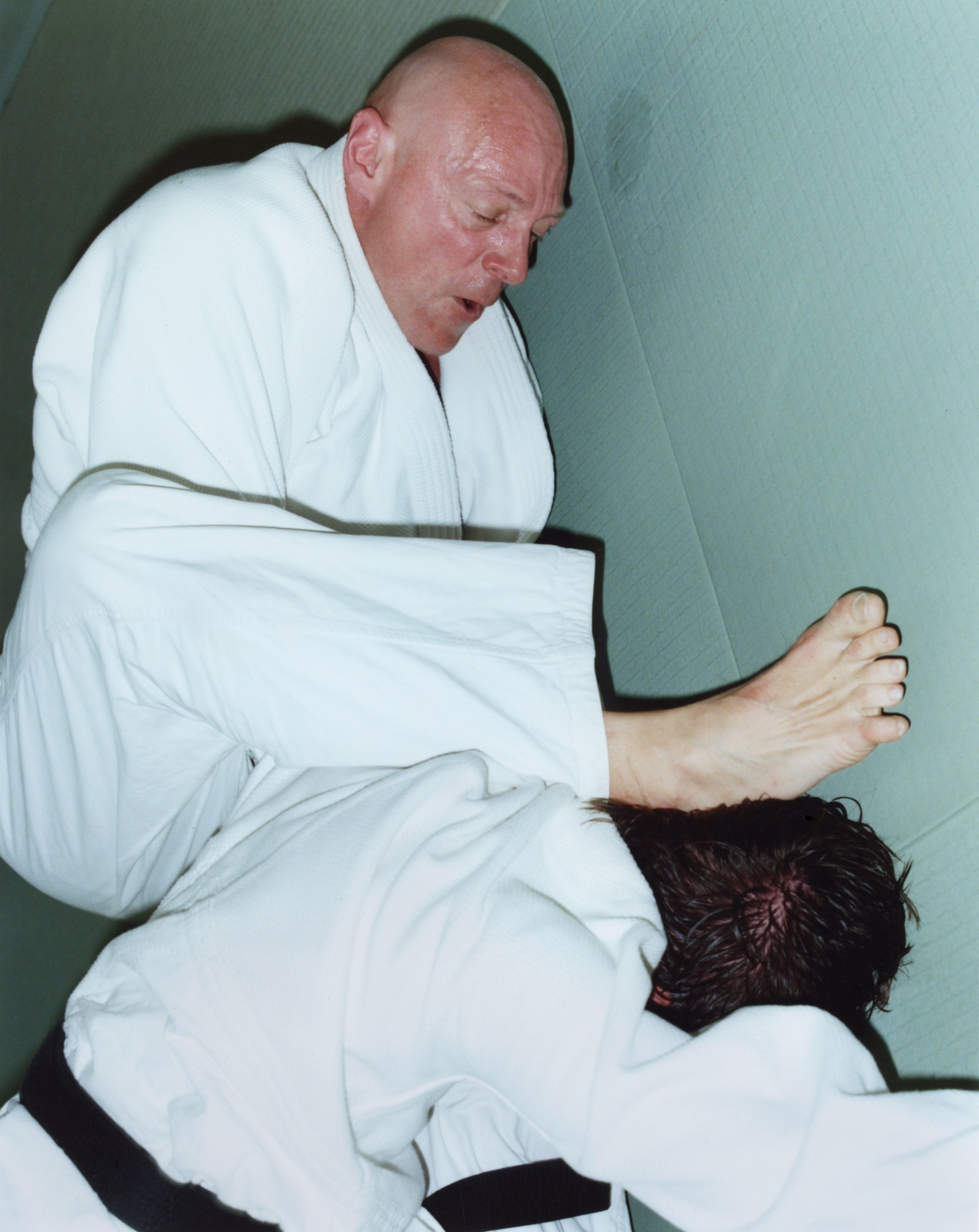 a bald man pins another man in a judo pose