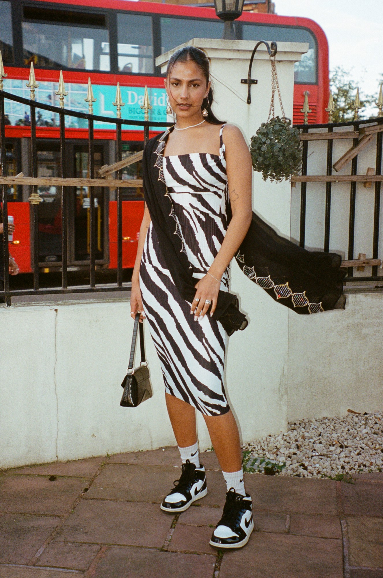 a south asian woman in a zebra dress wears a black scarf across her body