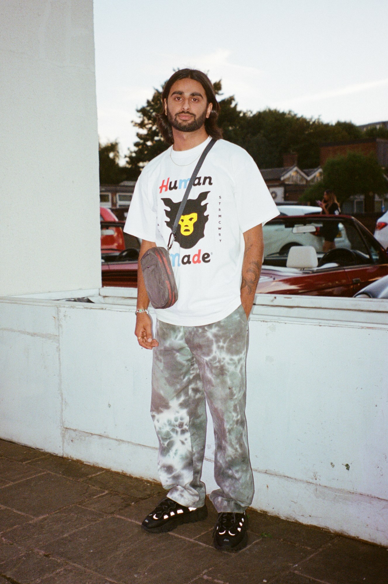 a young south asian man wearing tie dye trousers and a human made tee