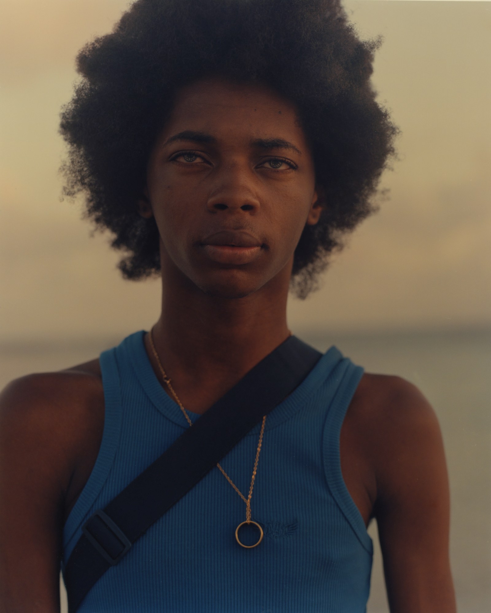 young man with afro in a blue tank top