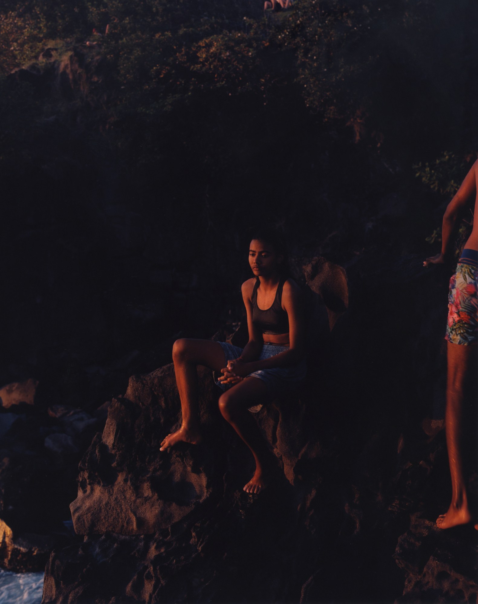 young person in sports bra and shorts on a rock