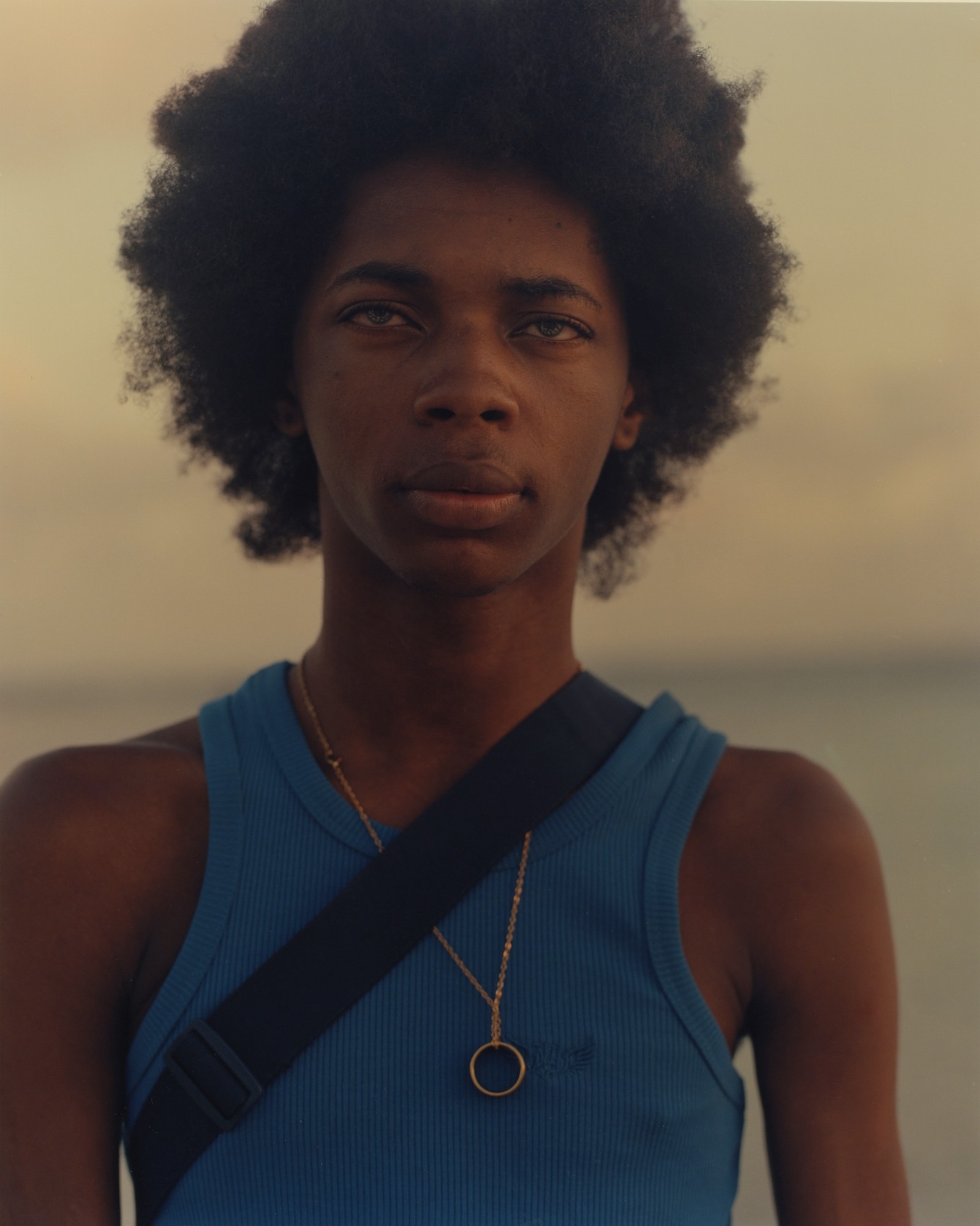 young person with afro, blue eyes and blue tank top