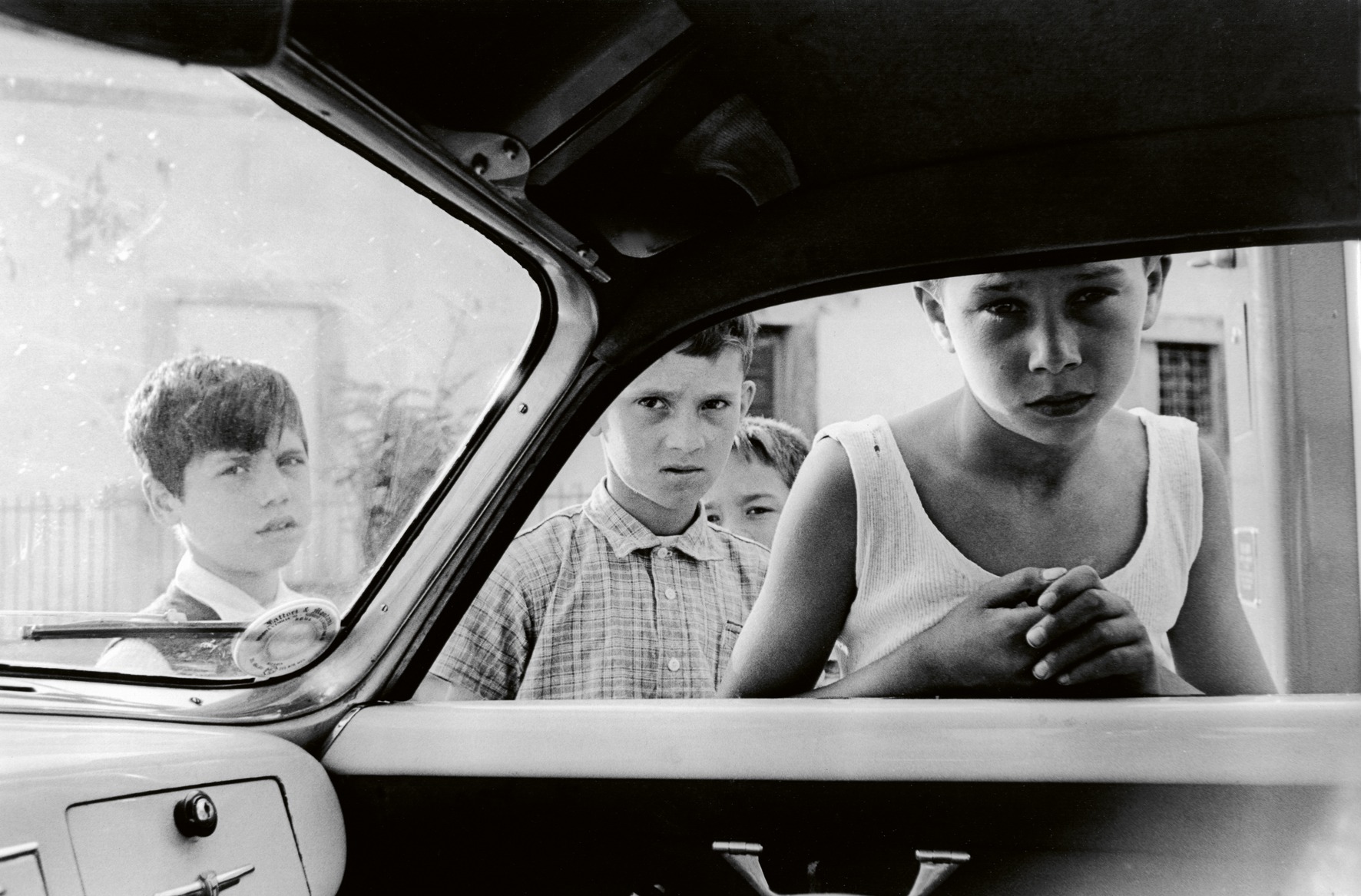 four young boys looking into a car window