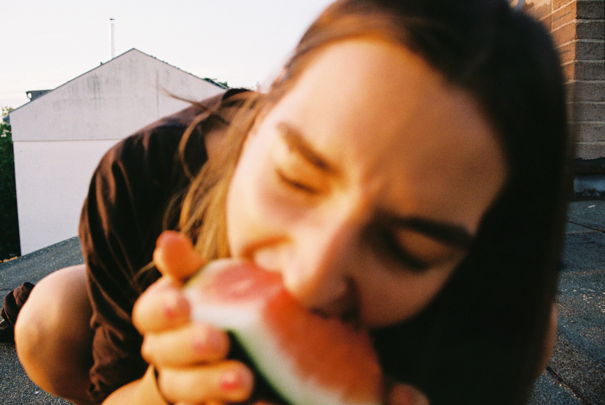 a blurry image of a woman eating a watermelon close to the lens