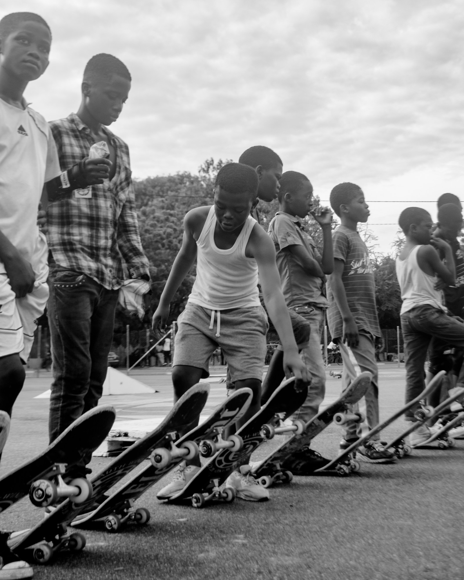 black-and-white image of a group of young skateboarders waiting in a line to begin skating