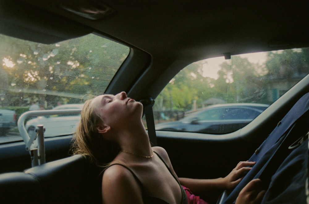 a girl in her car sleeping against the window