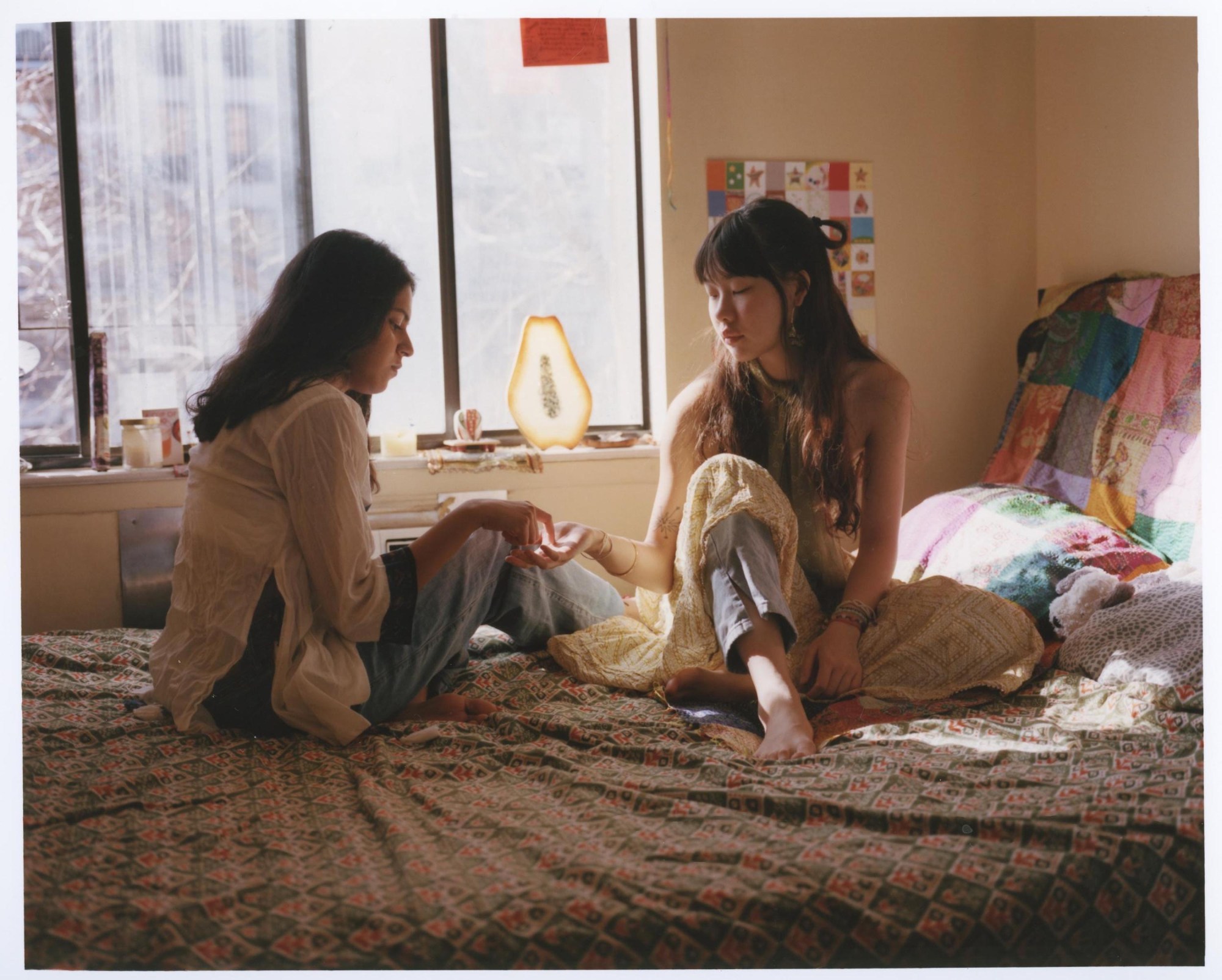 two women sitting on a bed with printed sheets