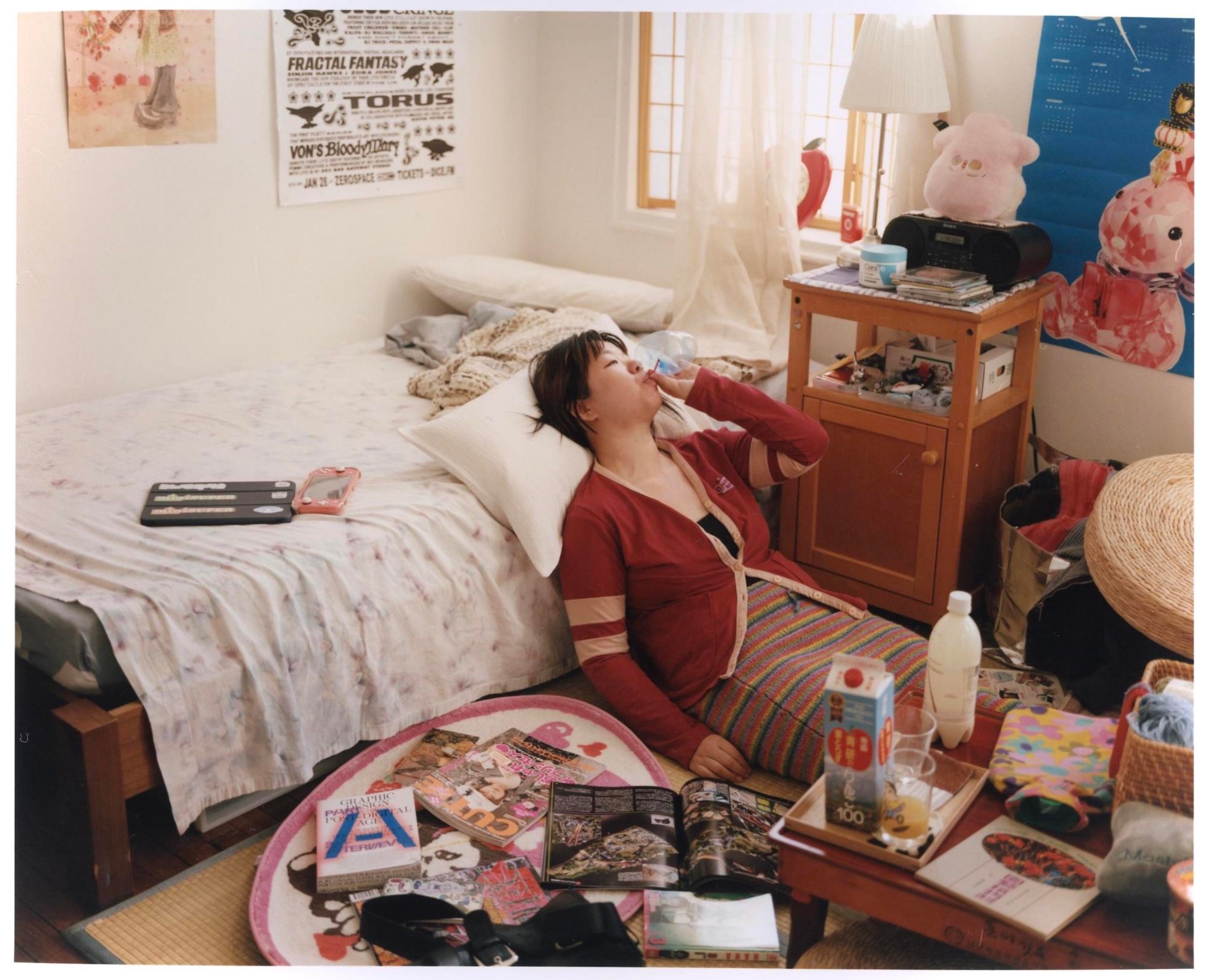 a young woman sitting on the floor of a messy bedroom