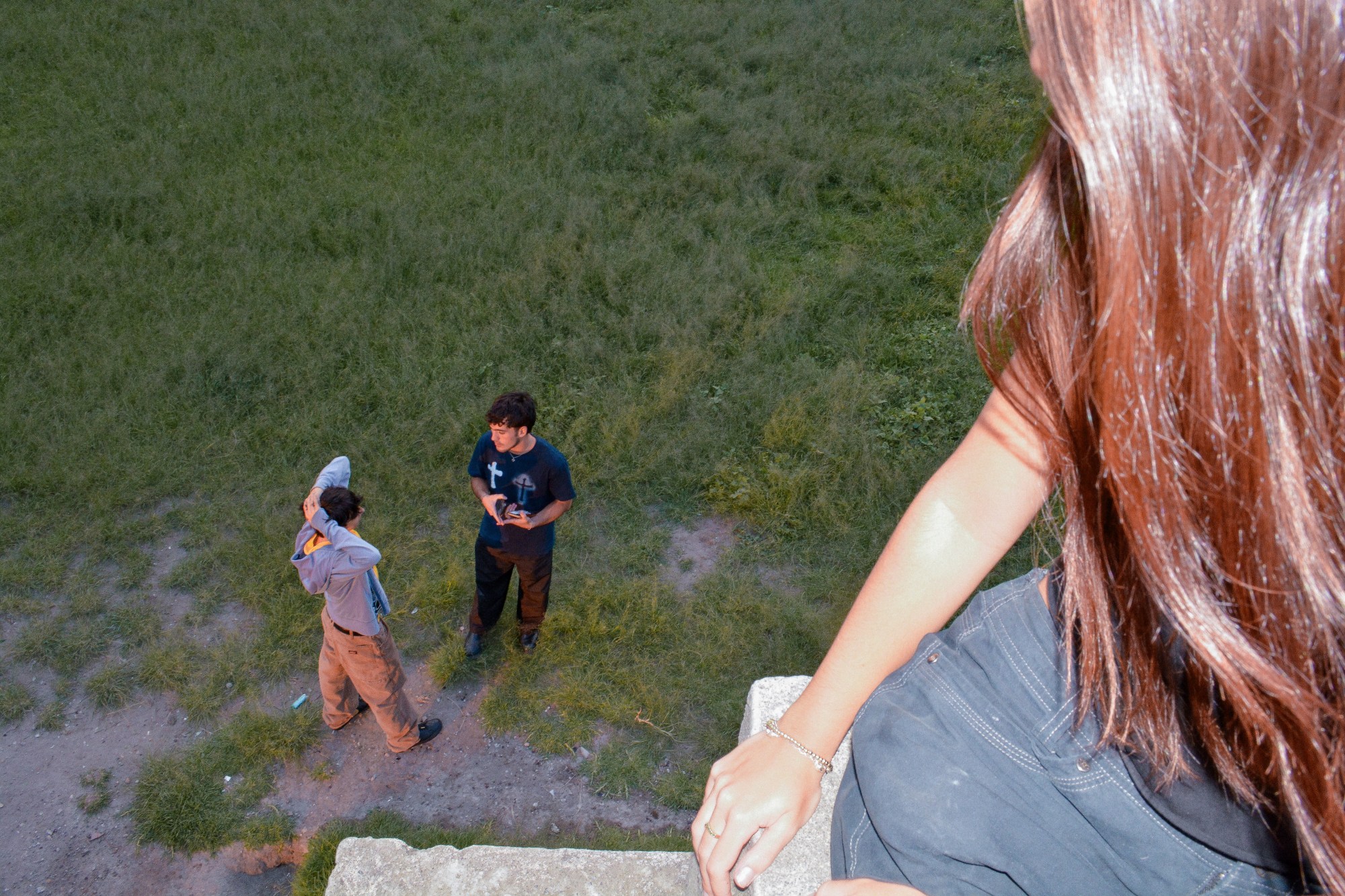 two teenagers in a field while a girl in the foreground looks on