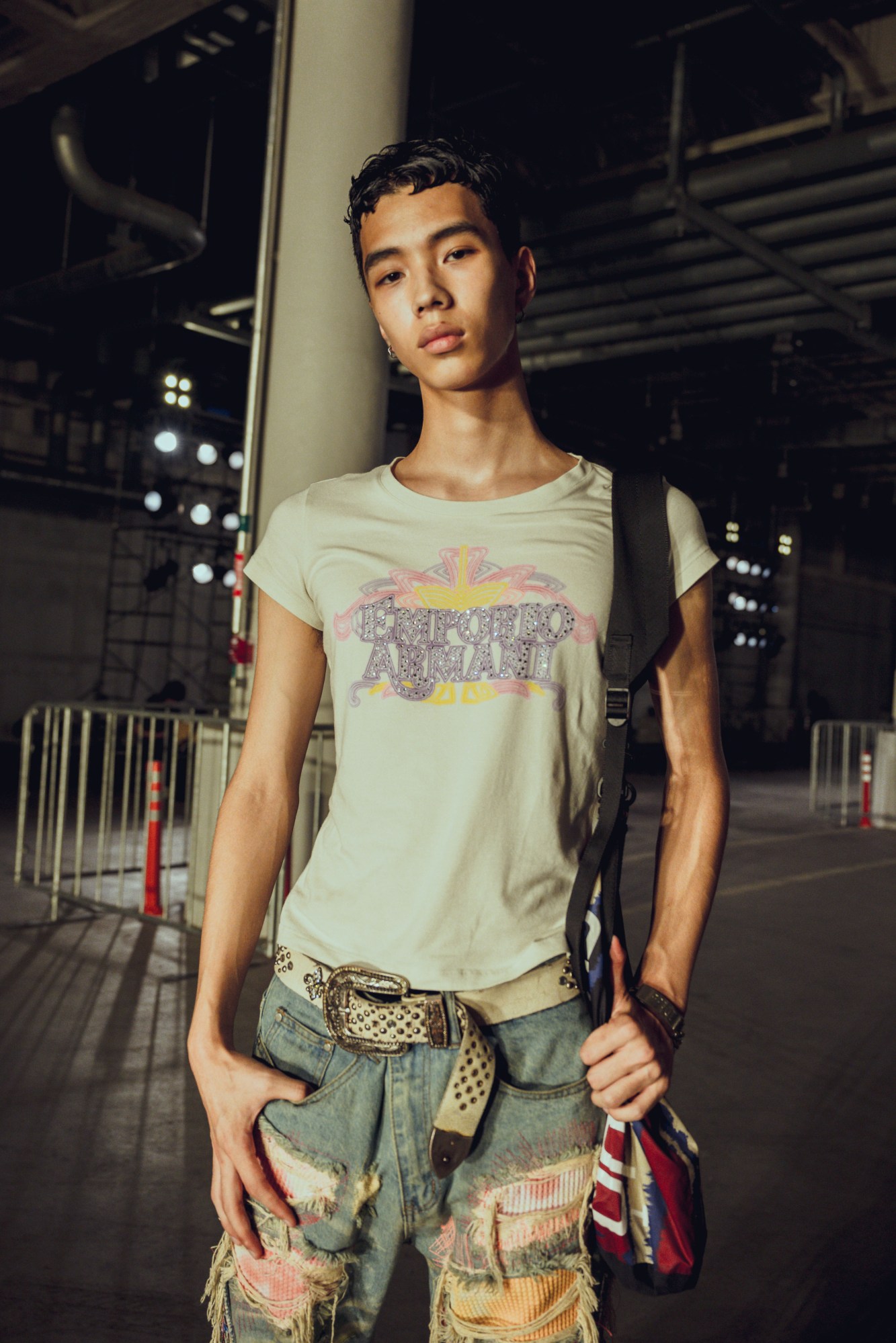 a young model wears distressed jeans, a studded western belt and a bejewlled ARMANI T-shirt