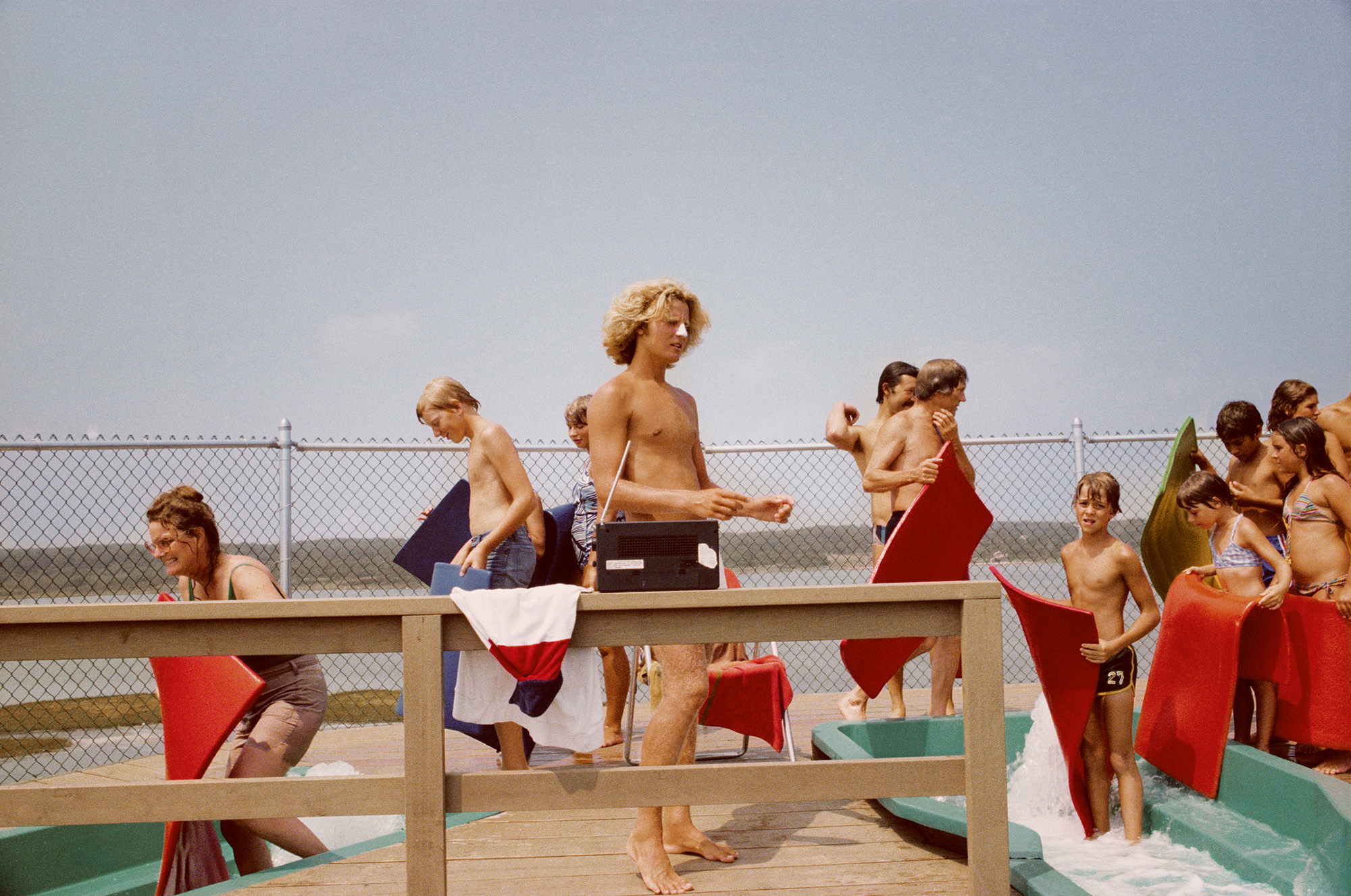 a lifeguard with white suncreen on his nose surrounded by swimmers ready to go down a waterslide