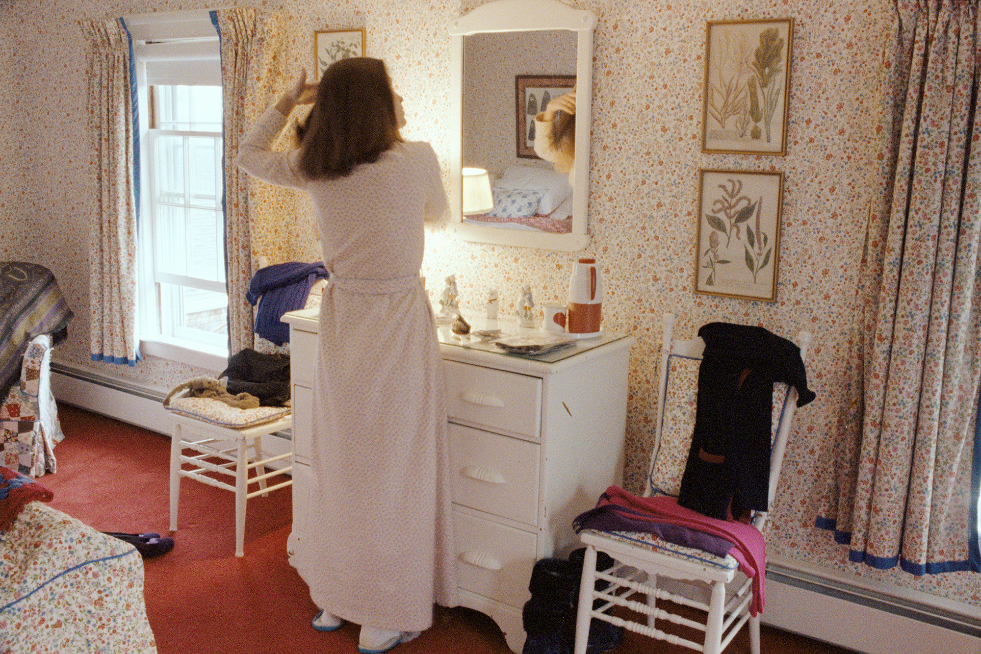 a woman brushing her hair in front of the mirror wearing a white robe