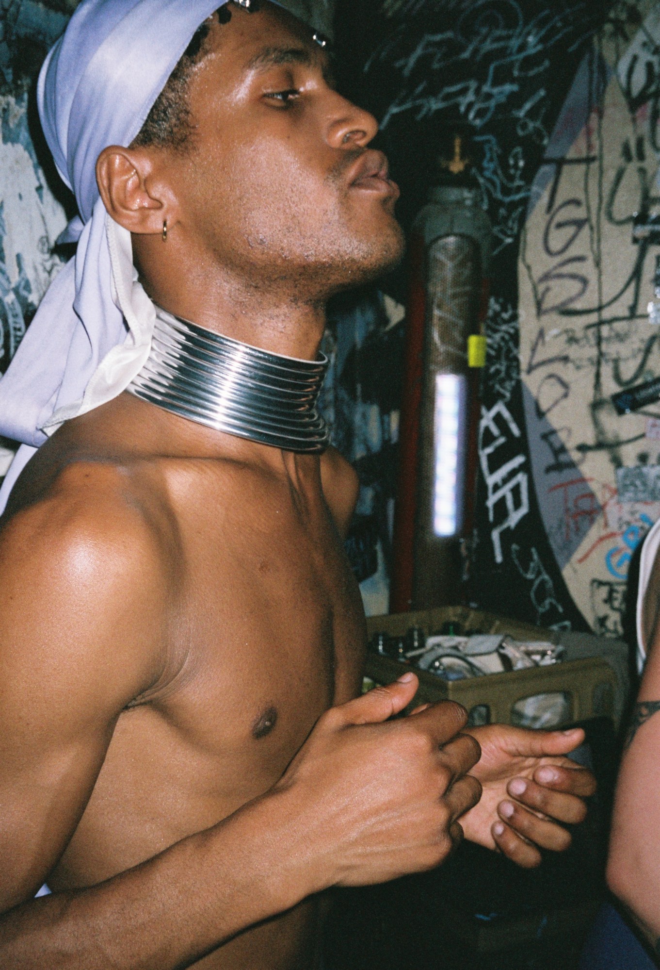 a young man in a lavendar durag and silver necklace at a party