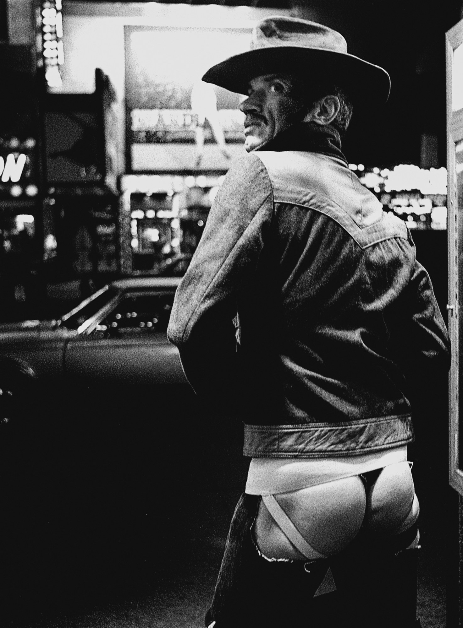 Miron Zownir photograph of a new york city man in a hat, denim jacket and jeans with the back pockets ripped out, showing his buttocks.