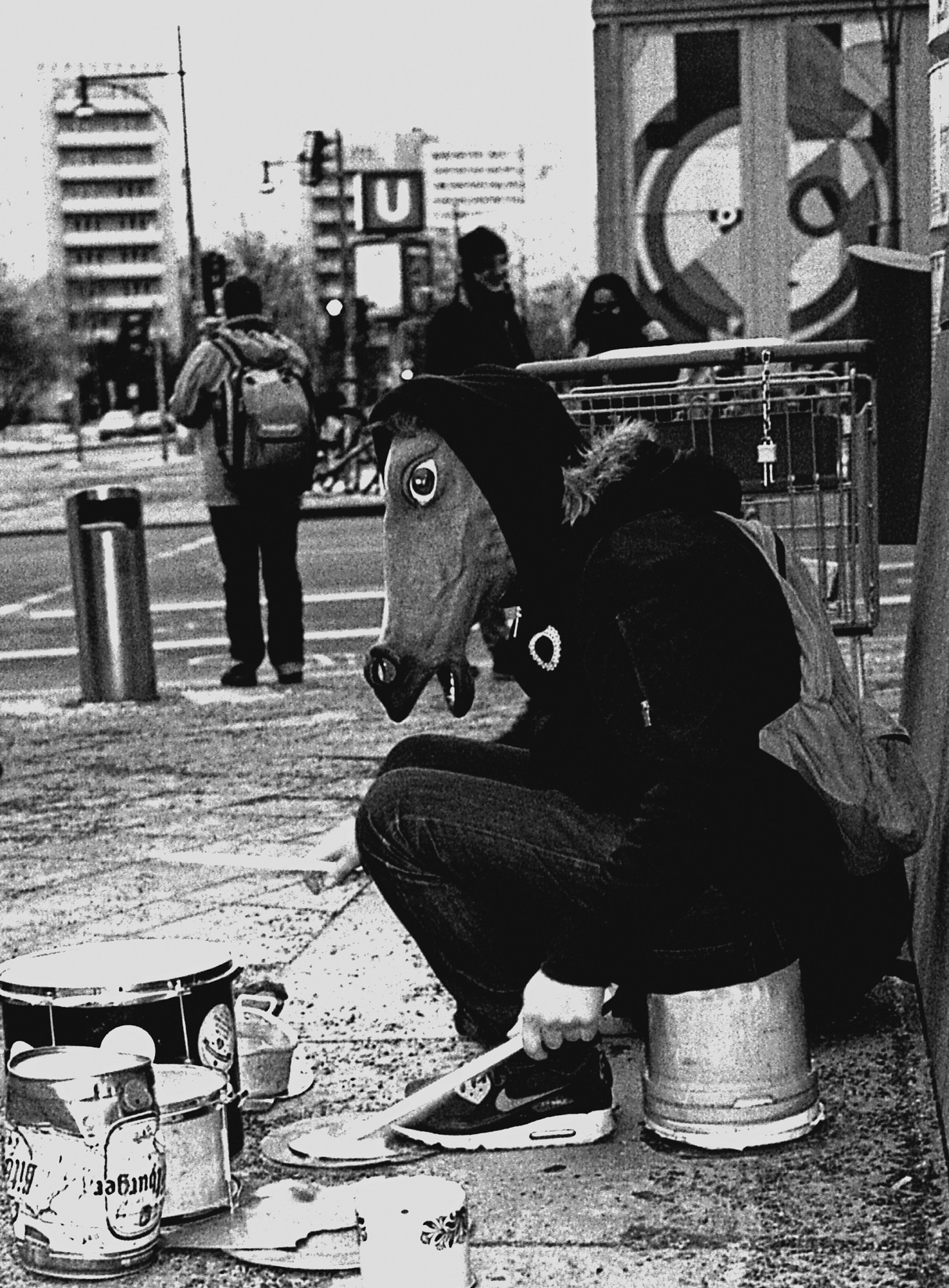 Miron Zownir photograph of a street performer in berlin playing the drums on a paint pot wearing a horse mask