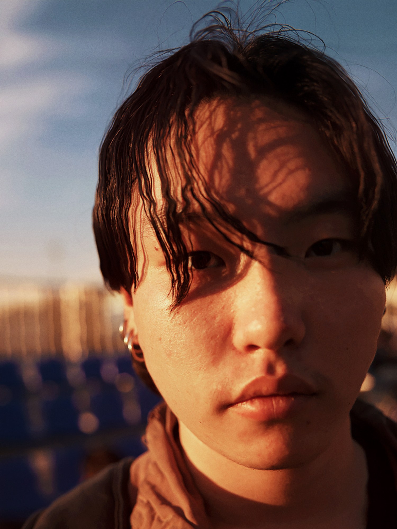 a young mongolian person with hooped earrings and short hair looks to camera