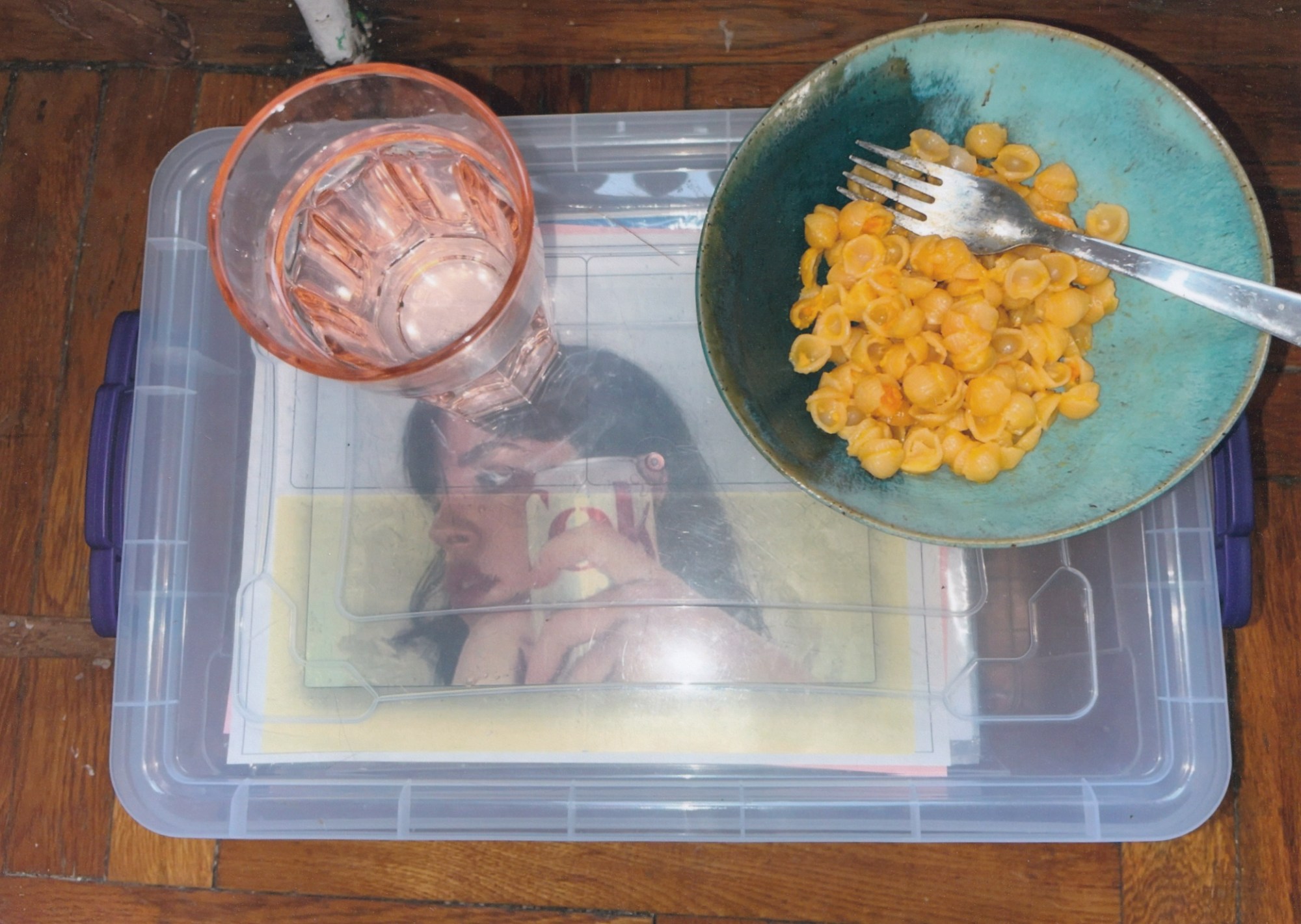 a pink water glass and a bowl of mac and cheese sitting on top of a clear crate