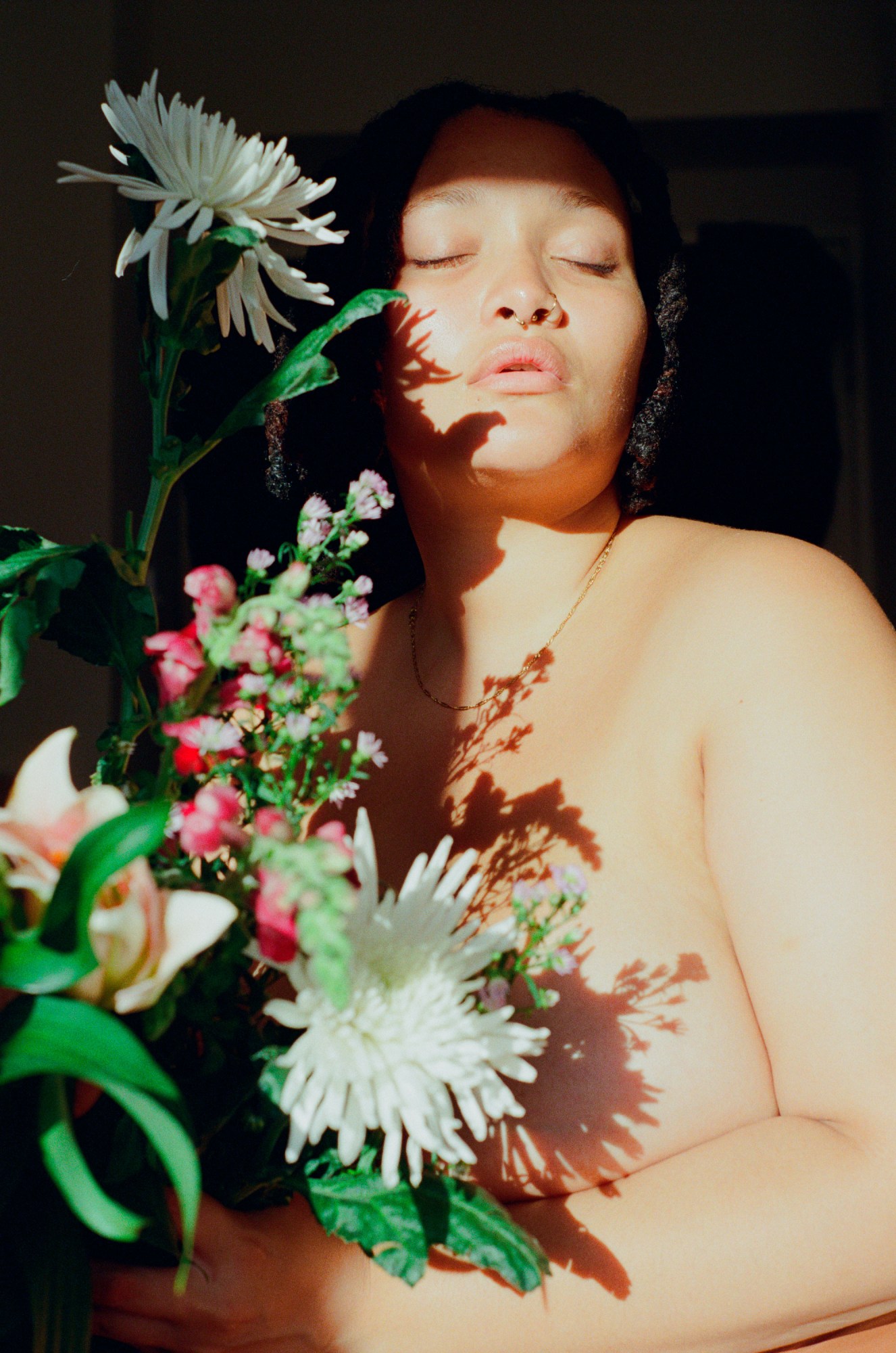 a woman posing partially nude for a self portrait while holding a bouquet