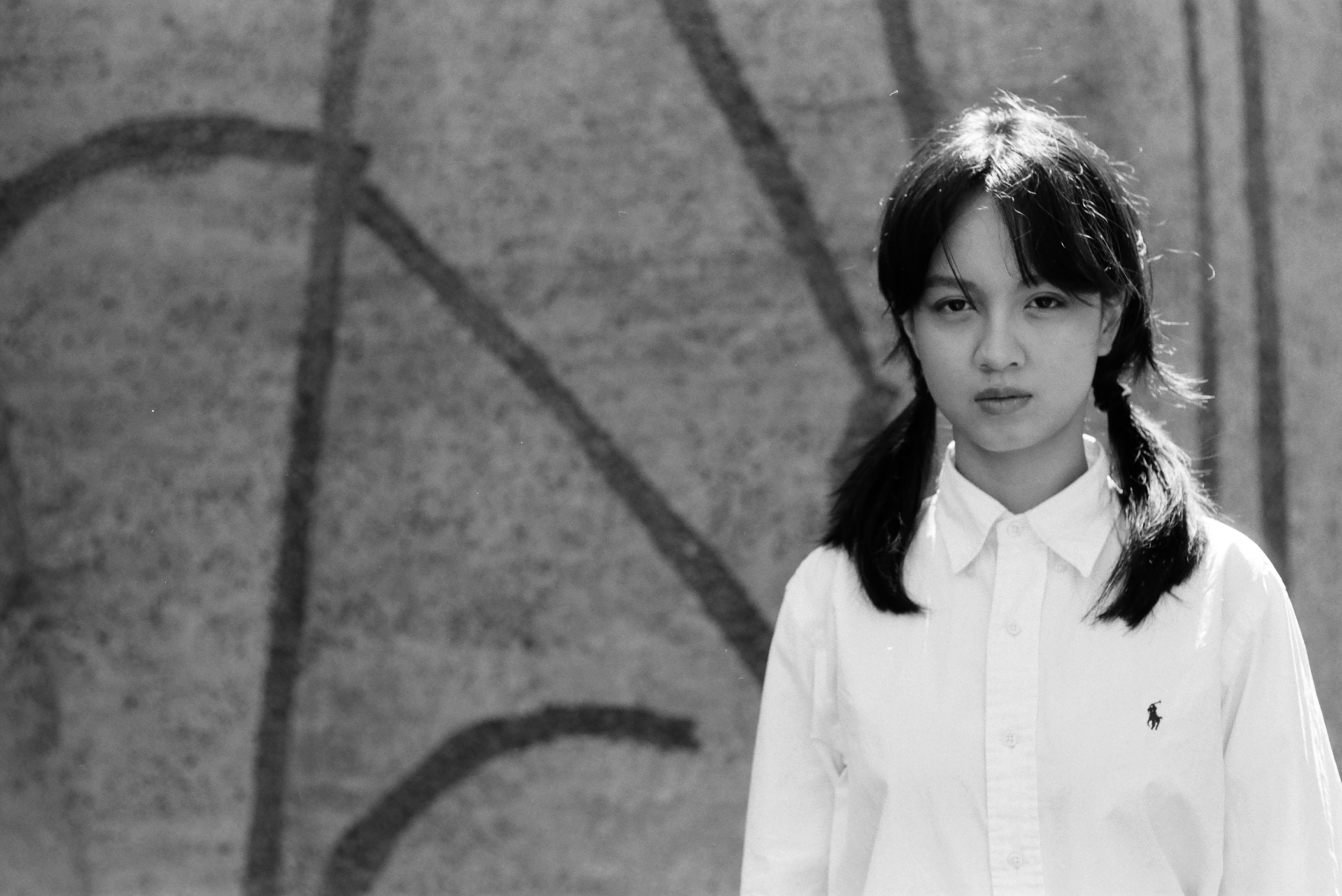 lucie zhang in front of a patterned concrete wall in a white button up