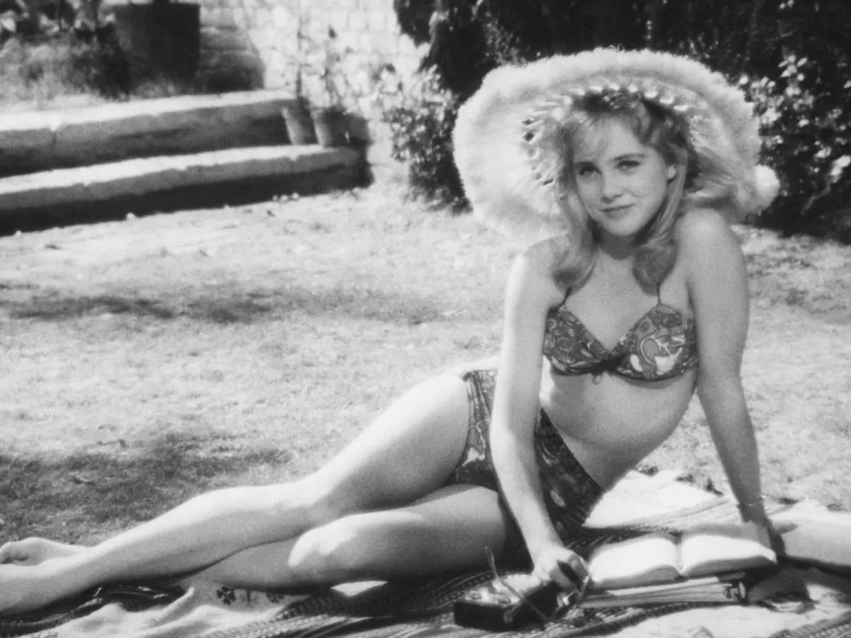 a still from Lolita (1962) in which the titular character is reading in the garden wearing a bikini