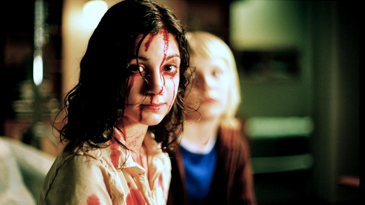 a still from Let the Right One In (2008) in which the child actors are sitting in a house, one covered in blood