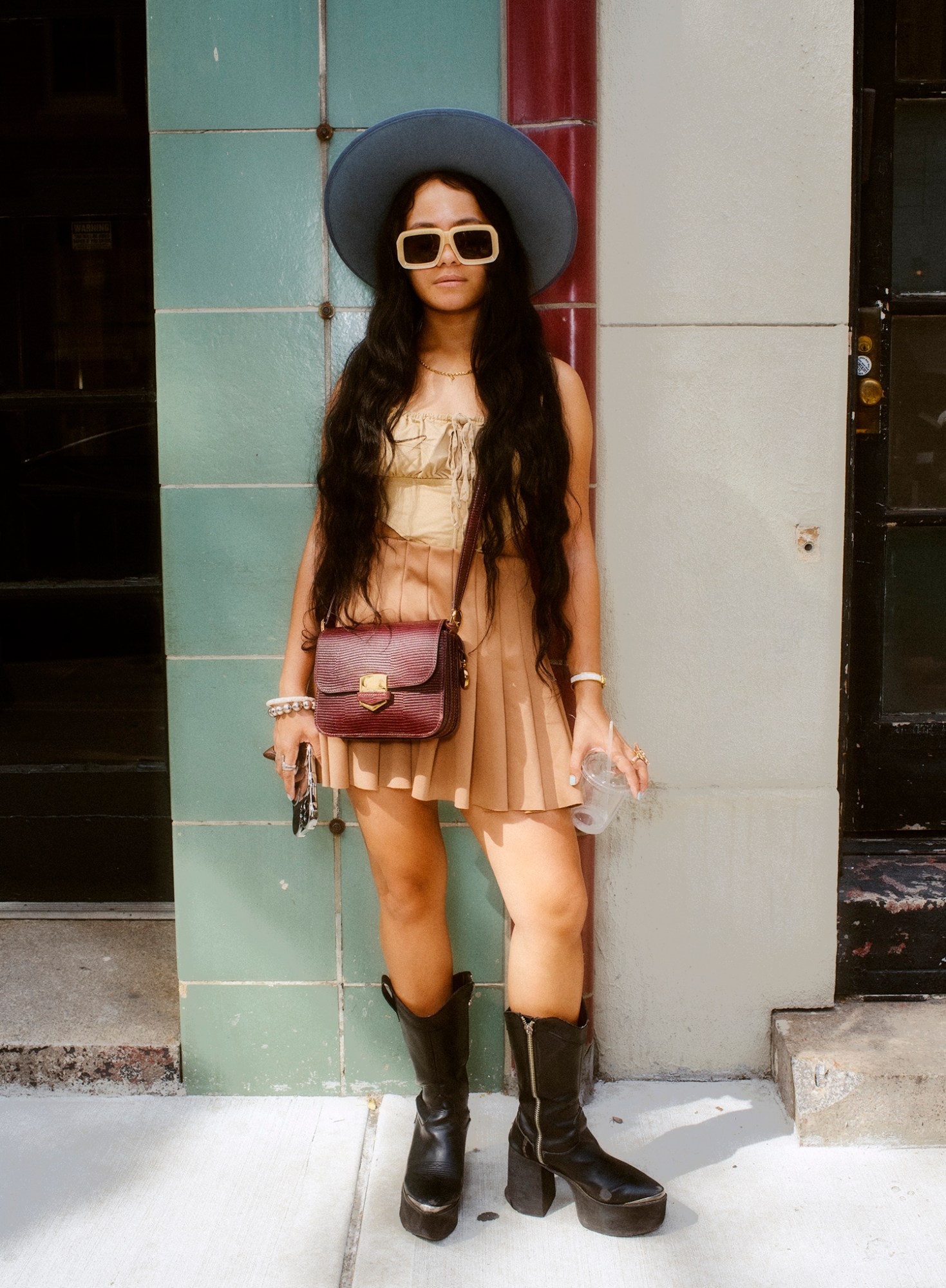 ashley markle photo of a sofia coppola fan on the streets of new york wearing black boots, a pleated skirt and a tied top.