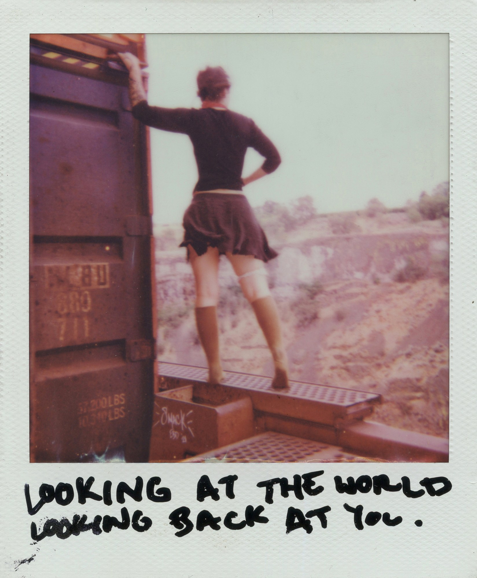 polaroid of slack looking out from outside of a train carriage captioned 'looking at the world looking back at you'