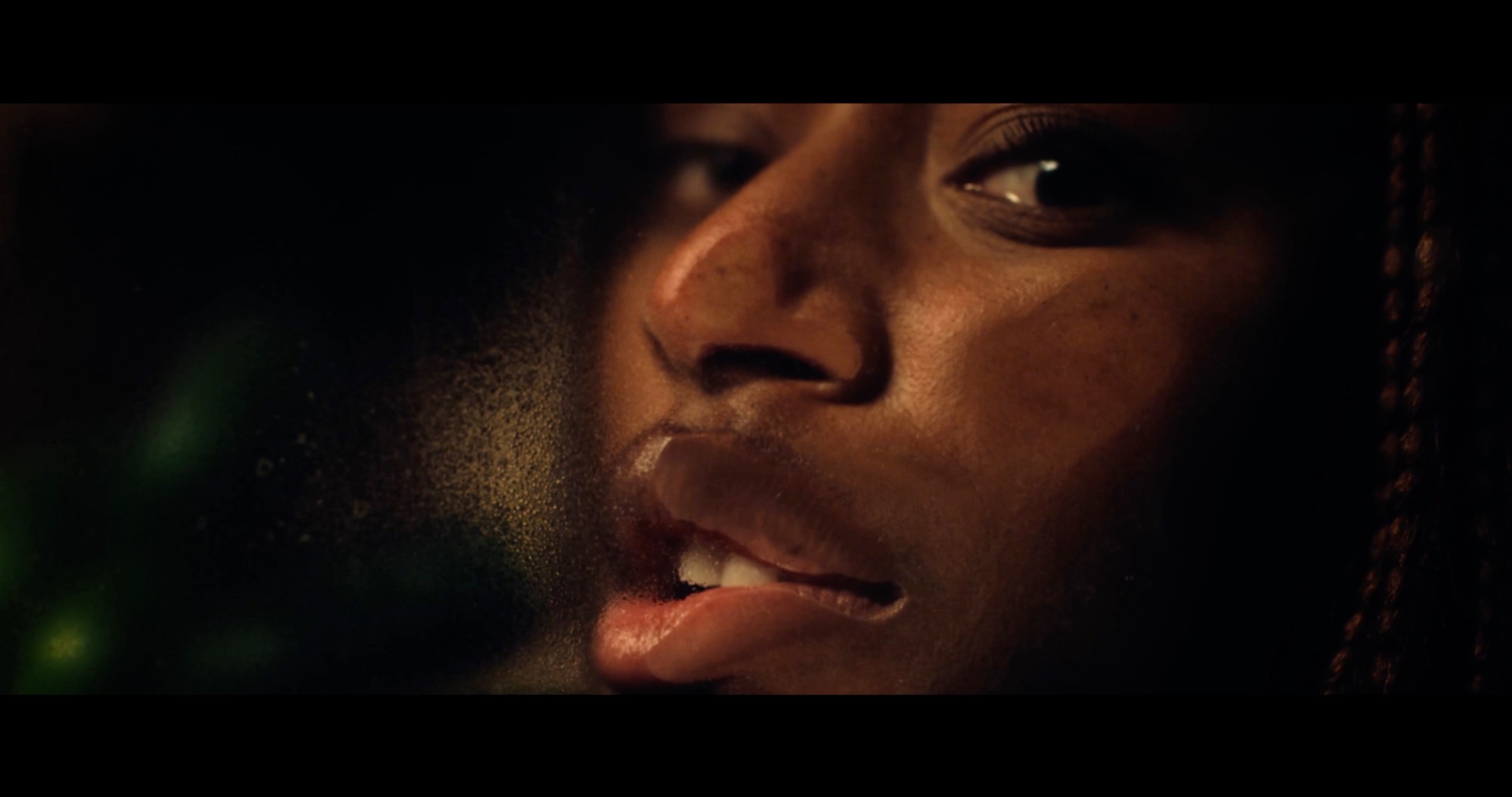 a close cropped image of a young Black person's face, partially squashed against a window, looking to camera