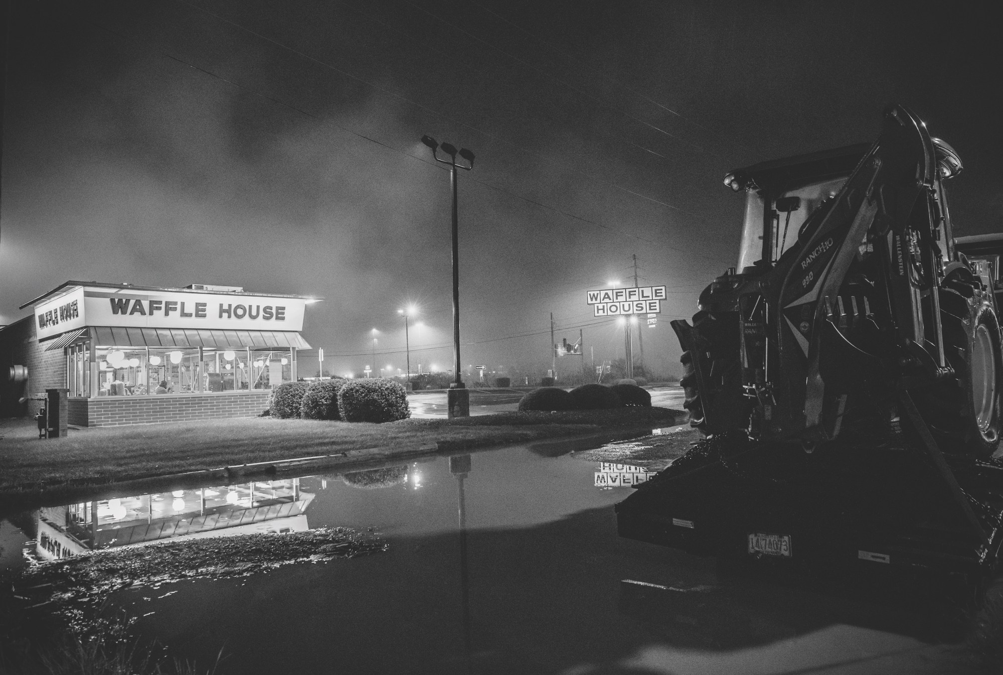 a black and white photo of a waffle house near a construction site and truck