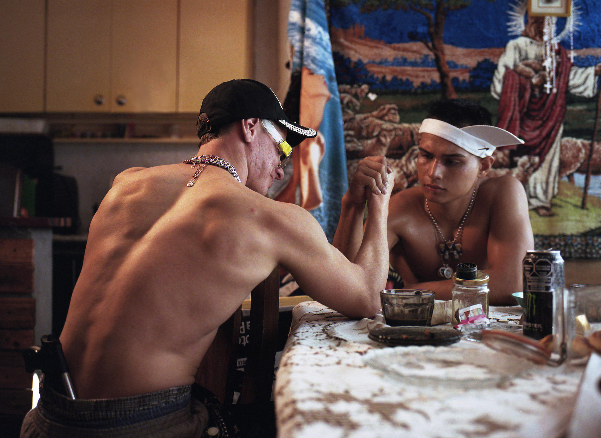 two men in a hat and an upside down visor arm wrestle