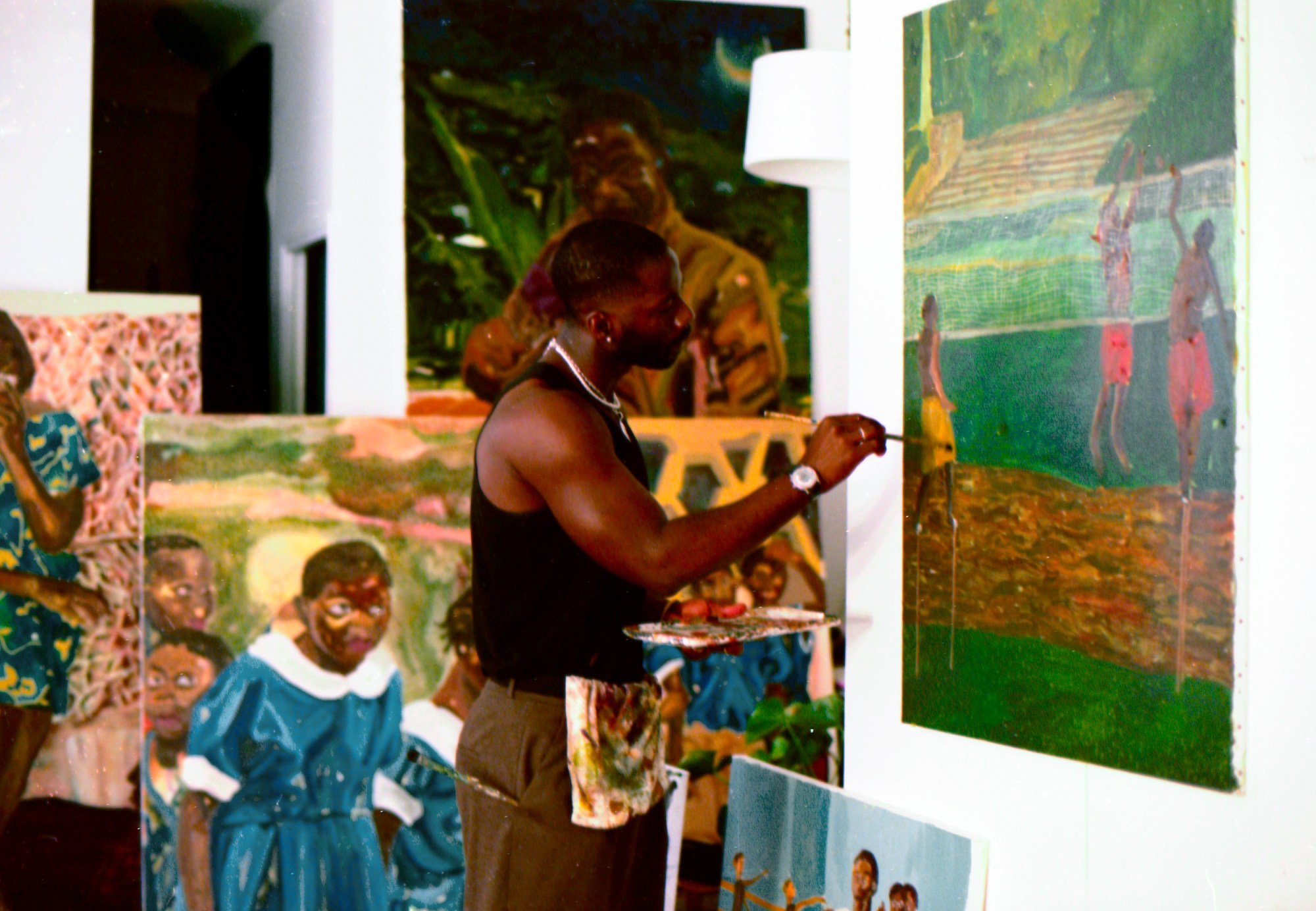 the artist Ludovic Nkoth painting a green canvas hung on his studio wall