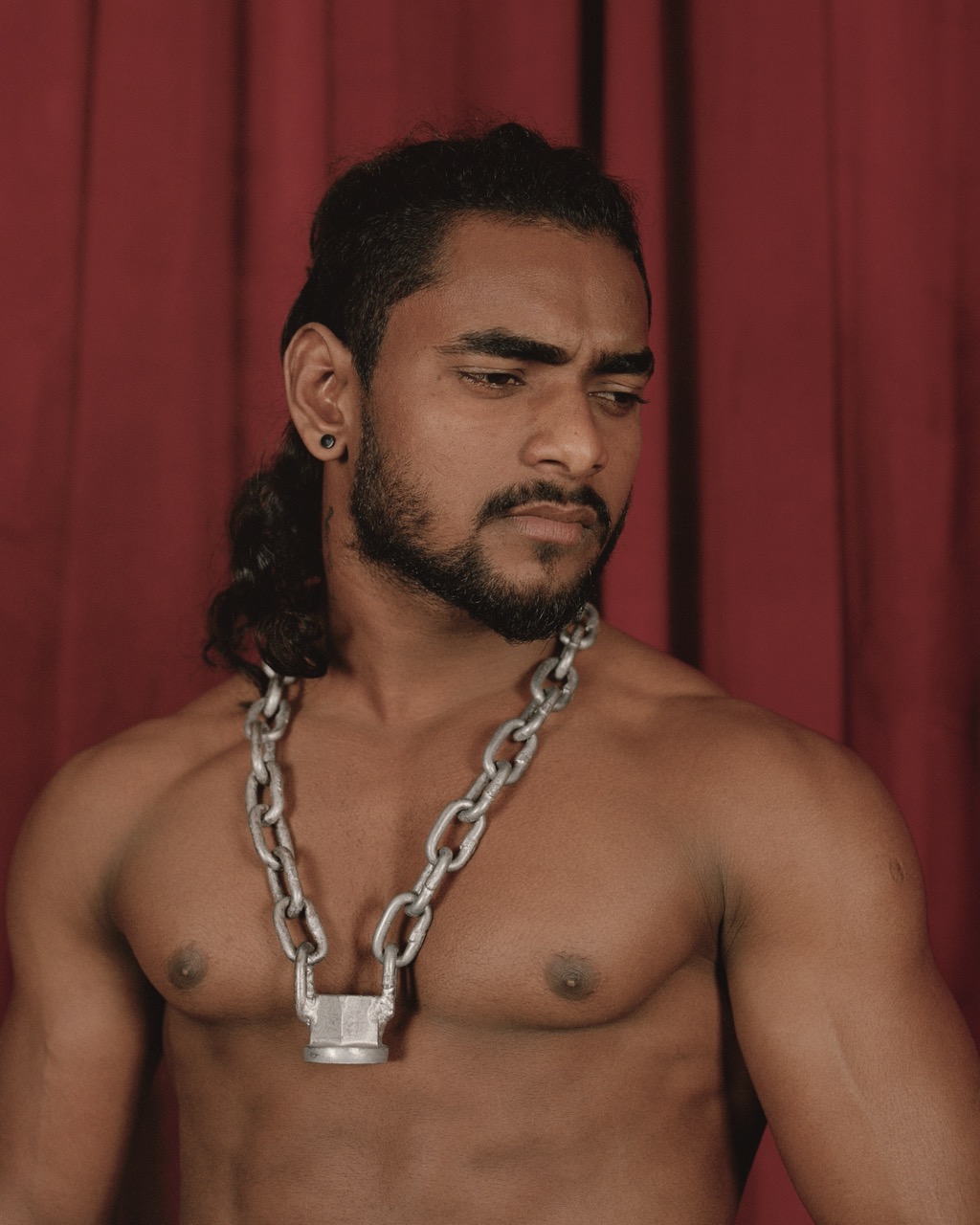 wrestler wearing silver chain while standing in front of a red curtain